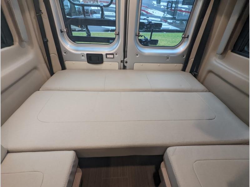 Inside an RV rental camper van: A large, light-colored, multi-section bed fills the rear, offering ample sleeping space.. Thor Sequence 2023