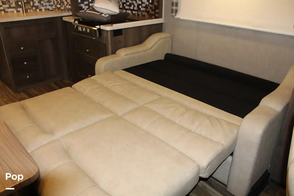 RV rental's versatile interior: a pull-out sofa bed in beige, a compact kitchen with wood cabinets. Great for travel.. Nexus RV Triumph Super C 2022