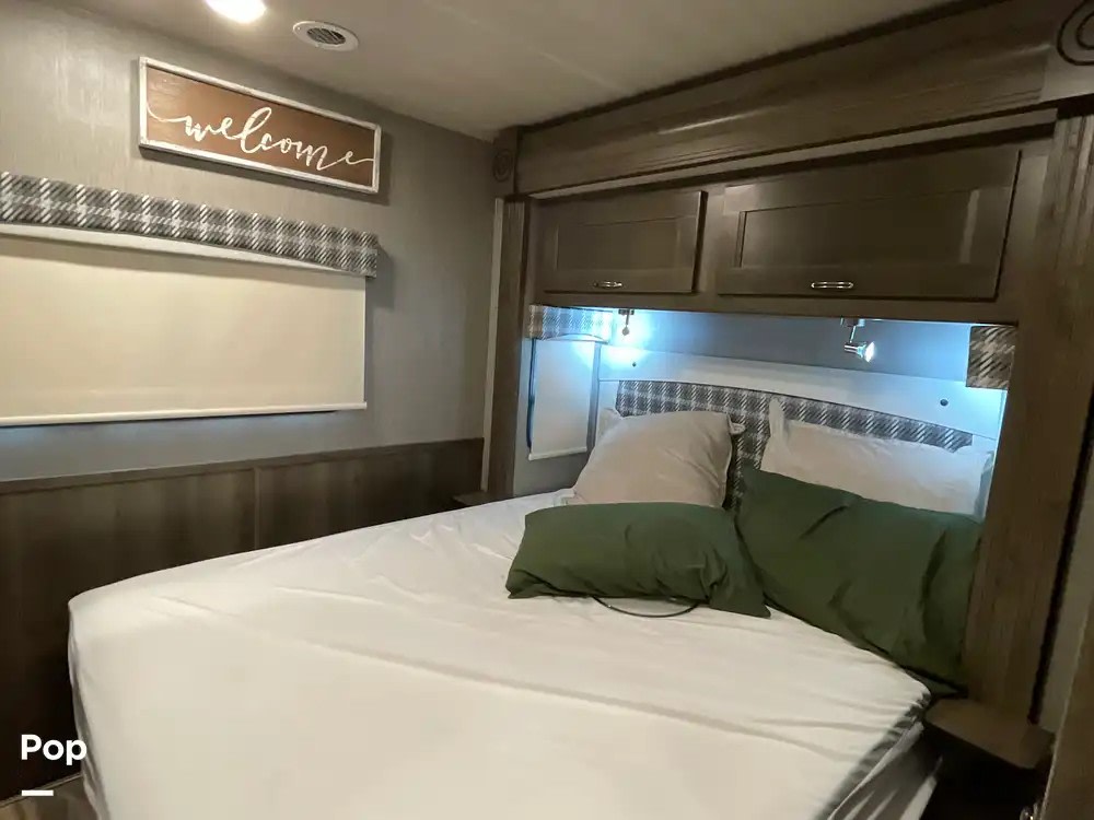 Cozy RV rental bedroom with comfortable bed, overhead storage, and reading lights for a comfortable stay.. Nexus RV Triumph Super C 2022