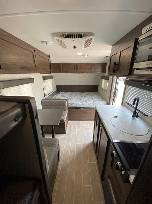 Compact RV rental interior featuring a full kitchen, dinette, rear bed, and bunk beds, offering comfort for travel adventures.. Cherokee Wolf Pup 2021