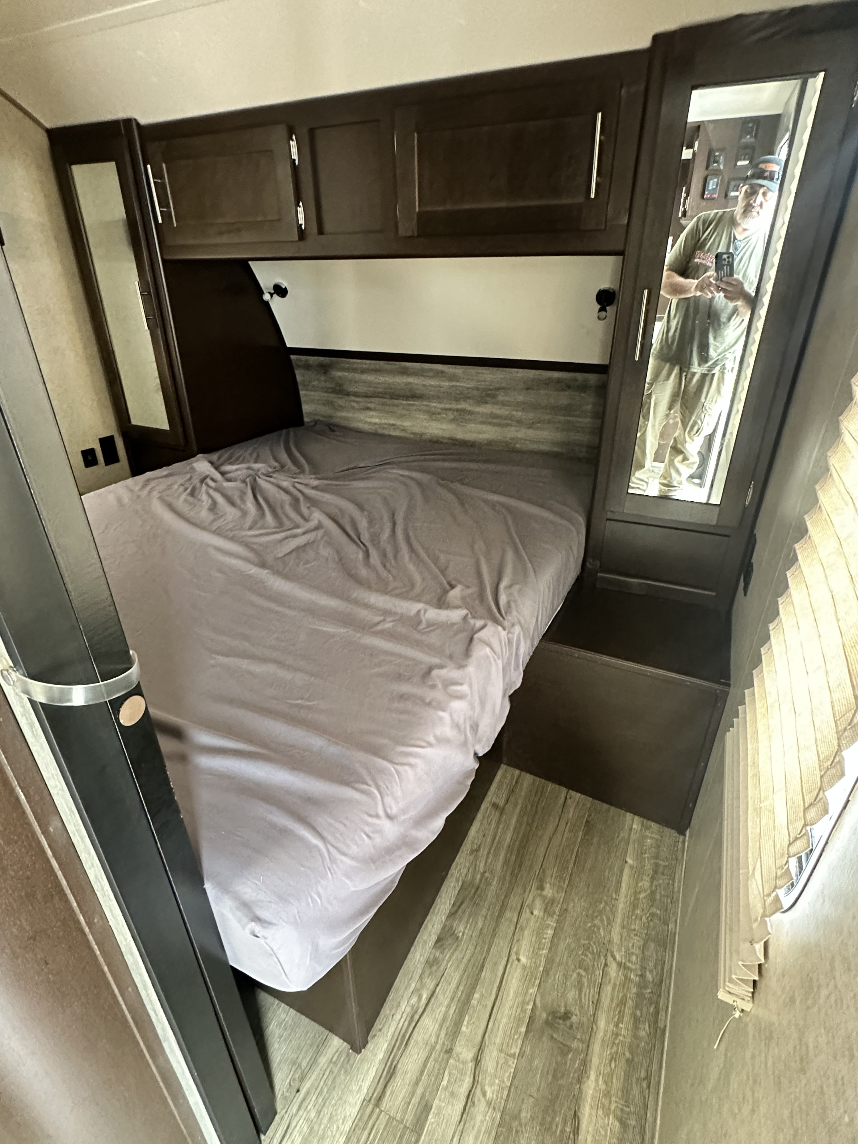 Explore this RV rental's compact bedroom with a made bed, overhead storage, and a convenient mirrored closet. Ideal for your next trip.. Forest River Cherokee Grey Wolf 2017