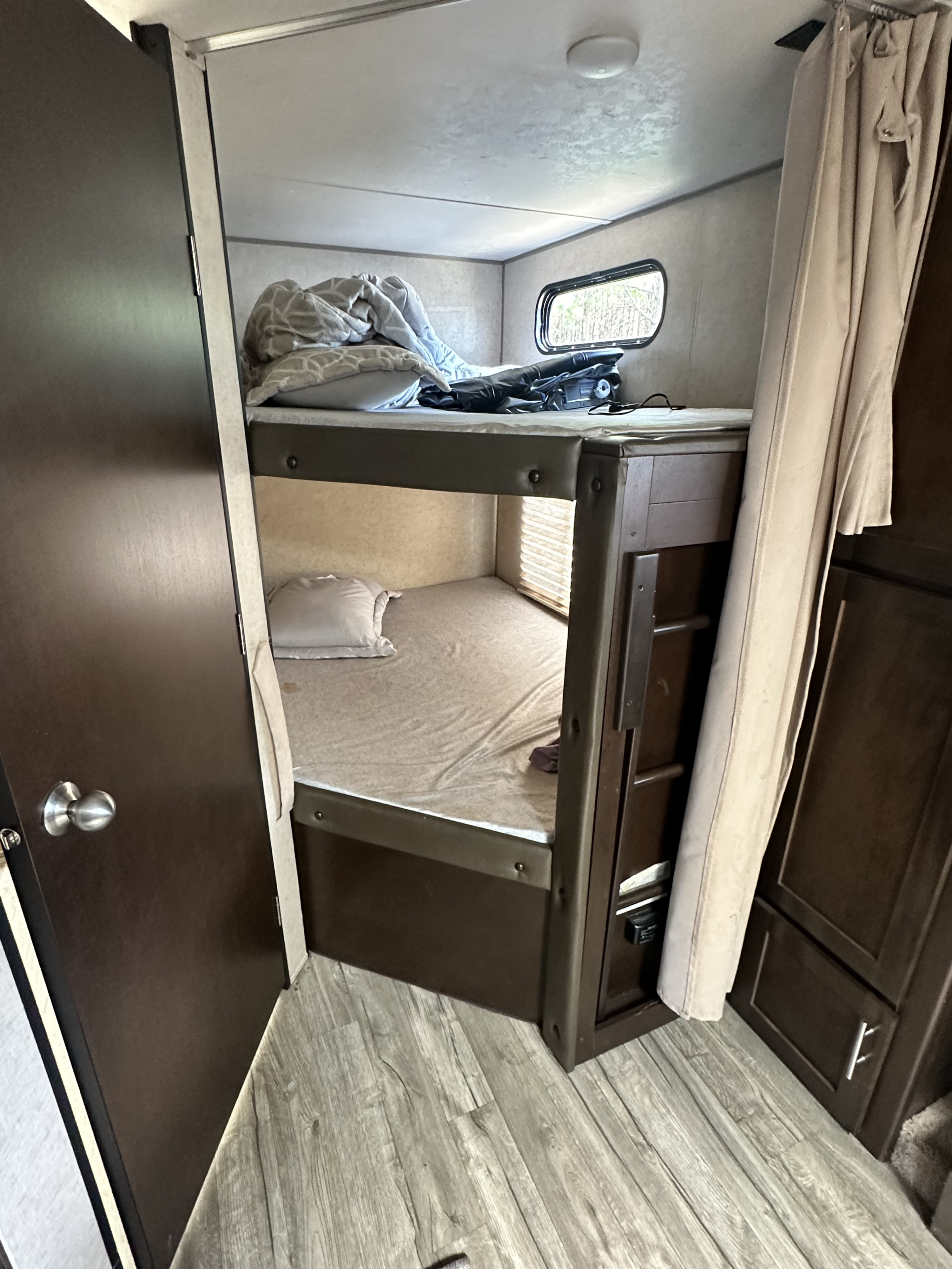 Cozy RV rental interior with bunk beds, showing a compact sleeping area with bedding and a window.. Forest River Cherokee Grey Wolf 2017