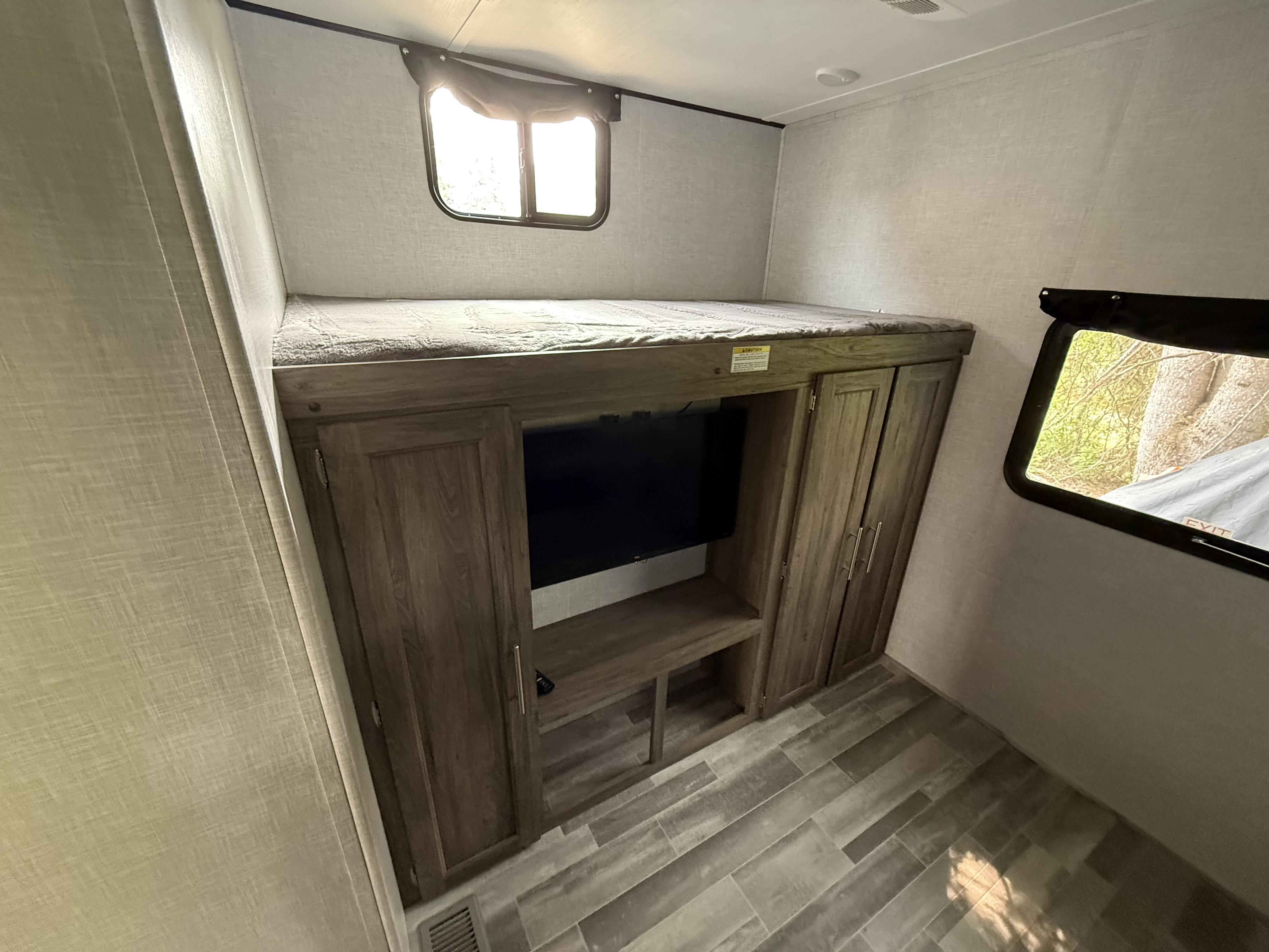 This RV rental bunkhouse features cozy sleeping, a built-in TV, and wardrobe storage for comfortable travel.. Crossroads Zinger 2025