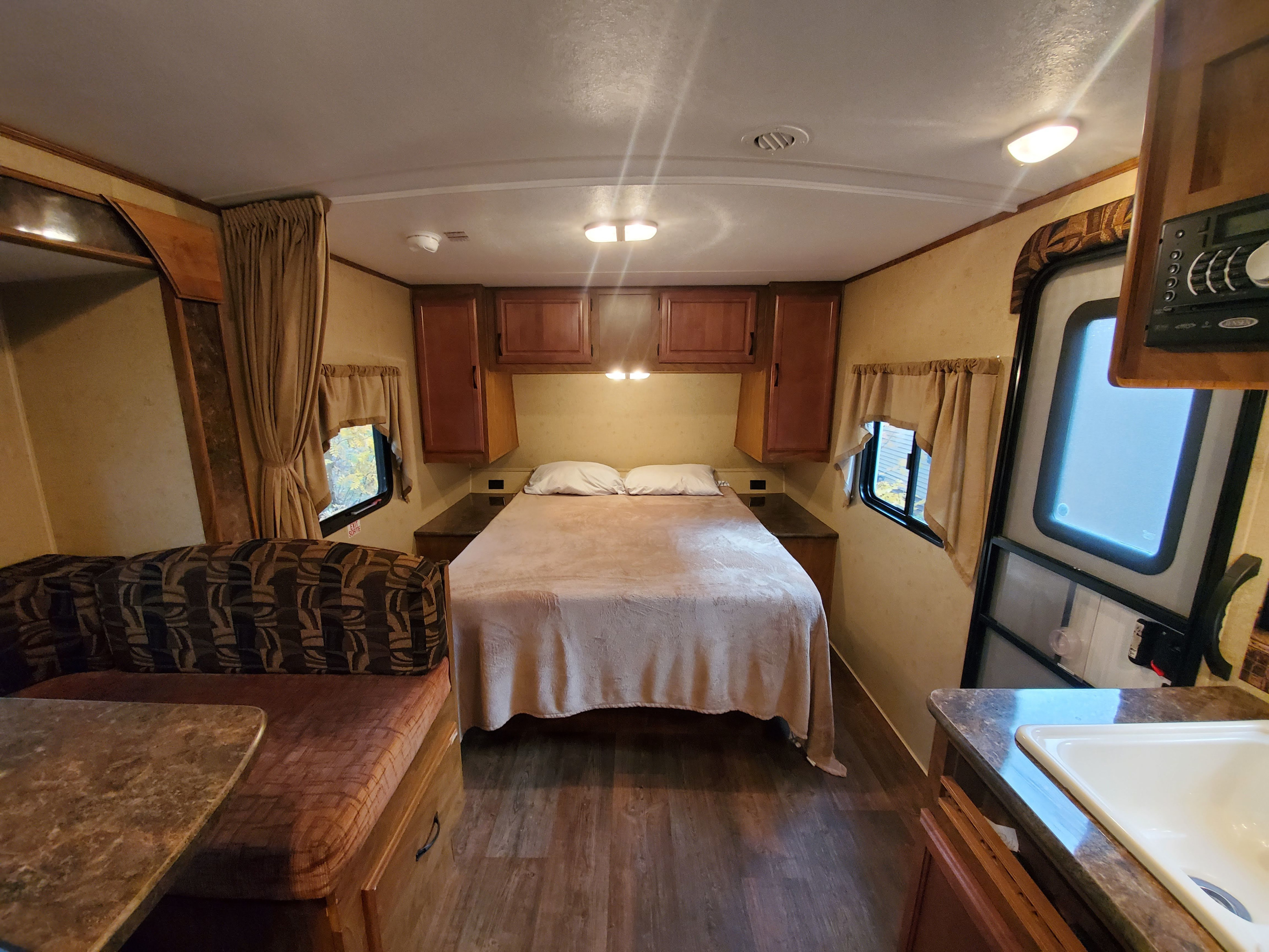 View of a well-appointed RV rental interior, showcasing the main bed, dinette seating, and kitchen sink. Ideal for road trips.. Black Rock Black Rock Trailer 2015