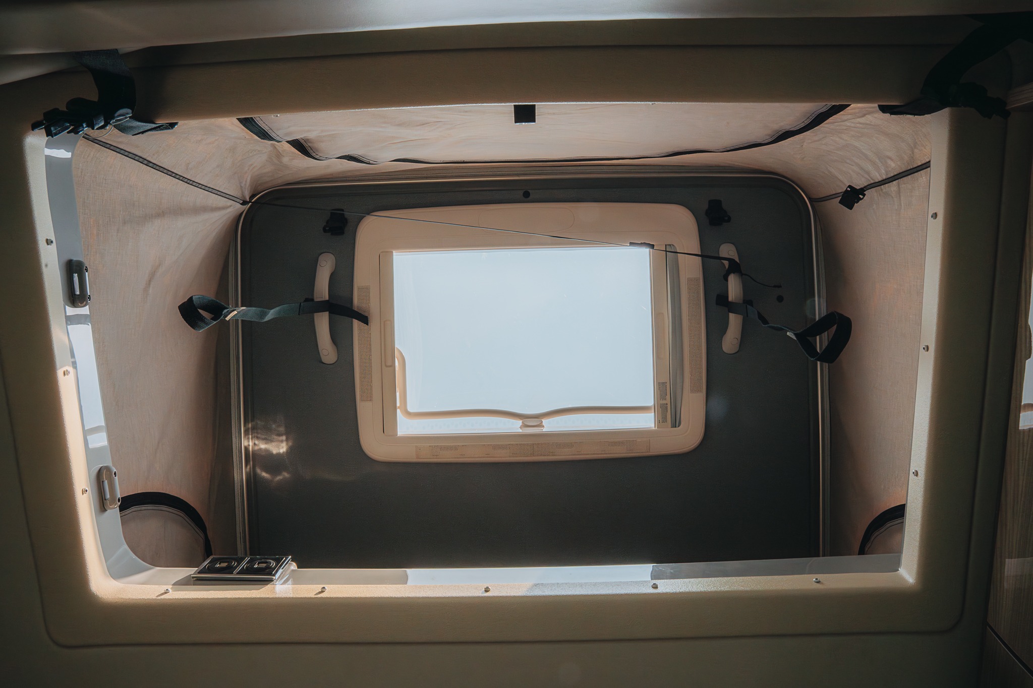 Bright camper van pop-top tent in an RV rental, showing an open window, fabric walls, and securing straps.. Thor Sequence 2023