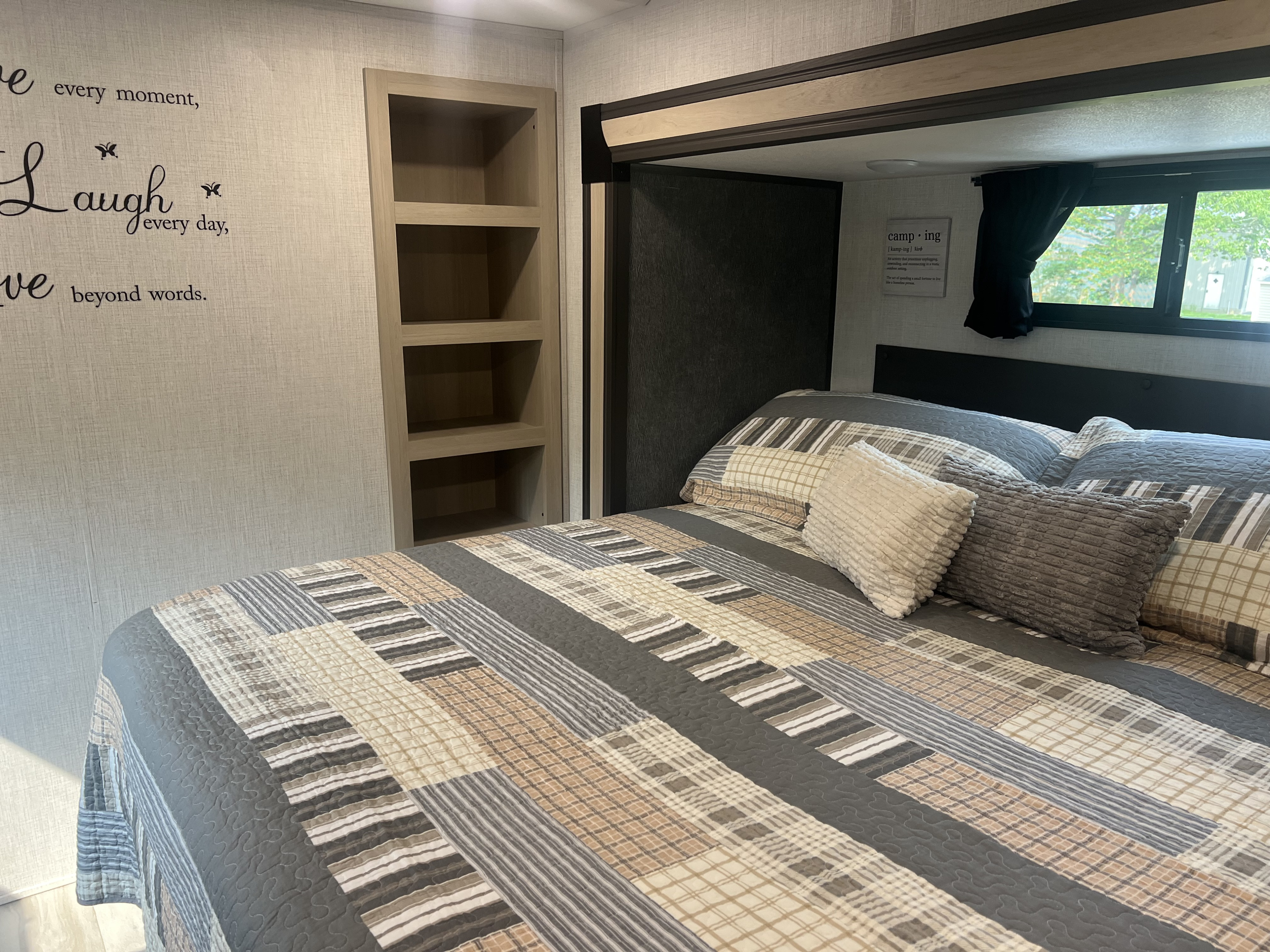 Cozy RV bedroom with patterned bedding, built-in storage, and camping decor, ideal for your RV rental.. Forest River Cardinal 2025