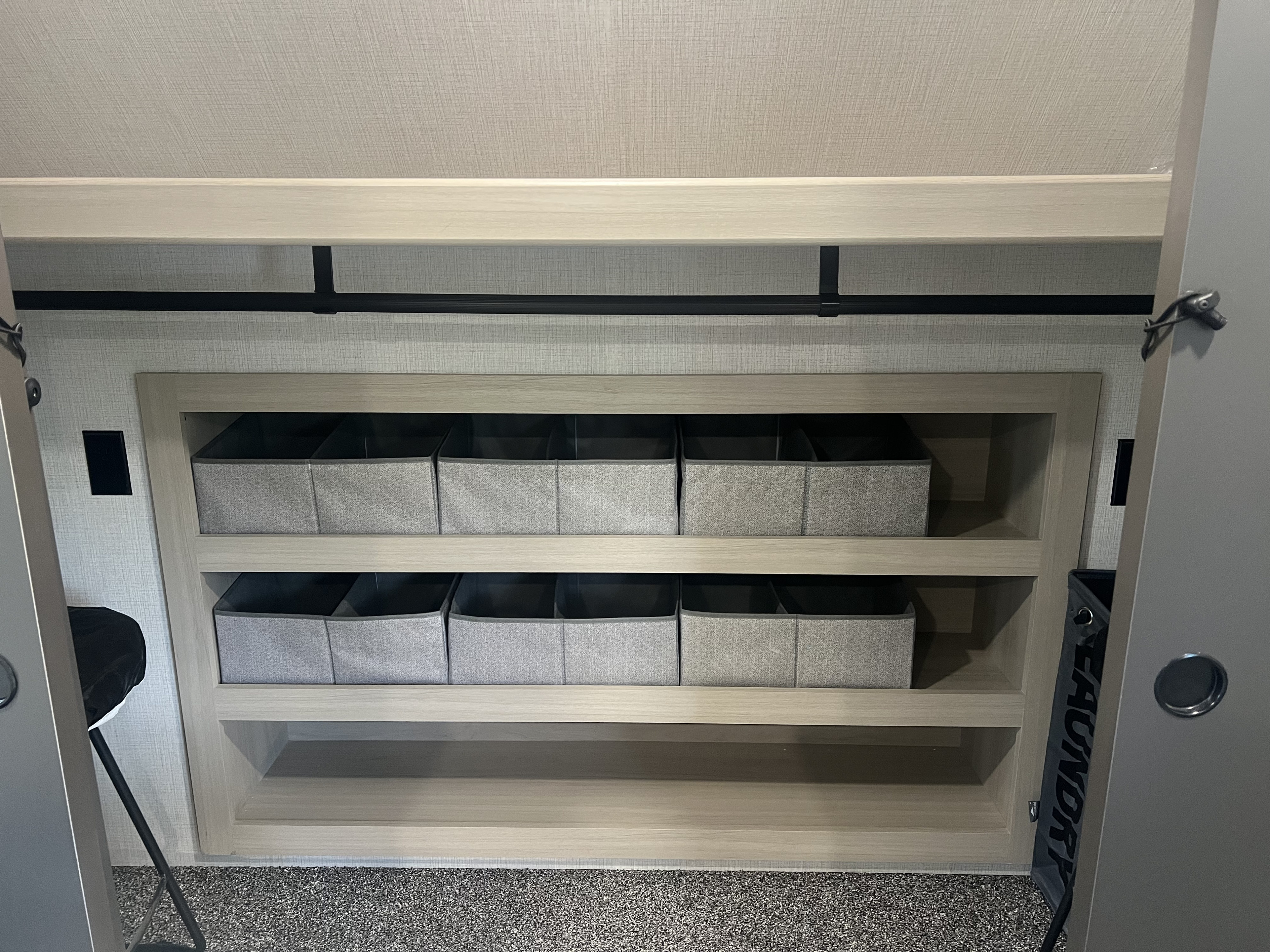 Well-organized RV rental closet features light wood shelves, fabric storage bins, a hanging rod, and a "LAUNDRY" bag.. Forest River Cardinal 2025