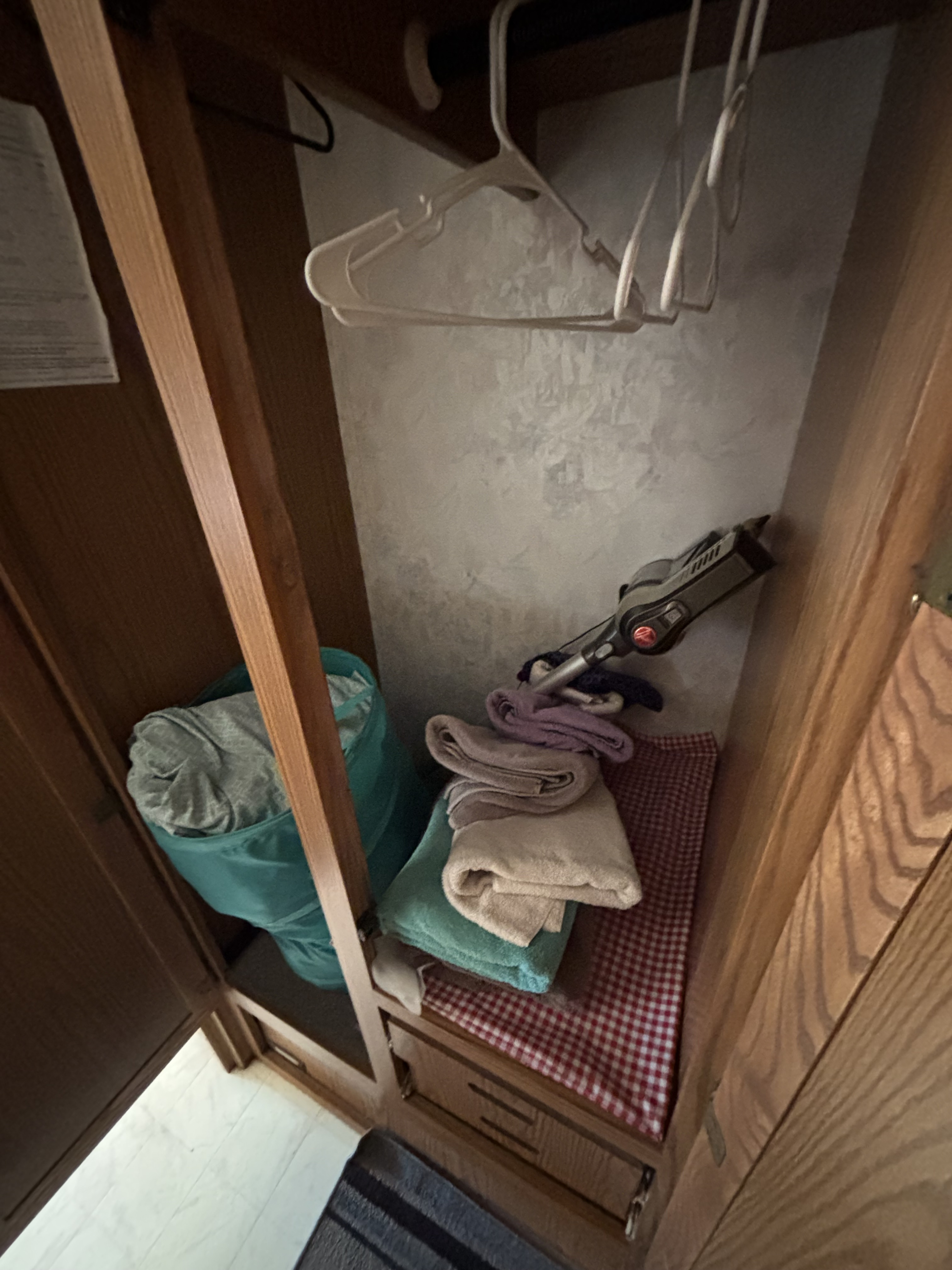 RV rental closet with hangers, a handheld vacuum, and folded towels for efficient storage.. Winnebago Brave 1997