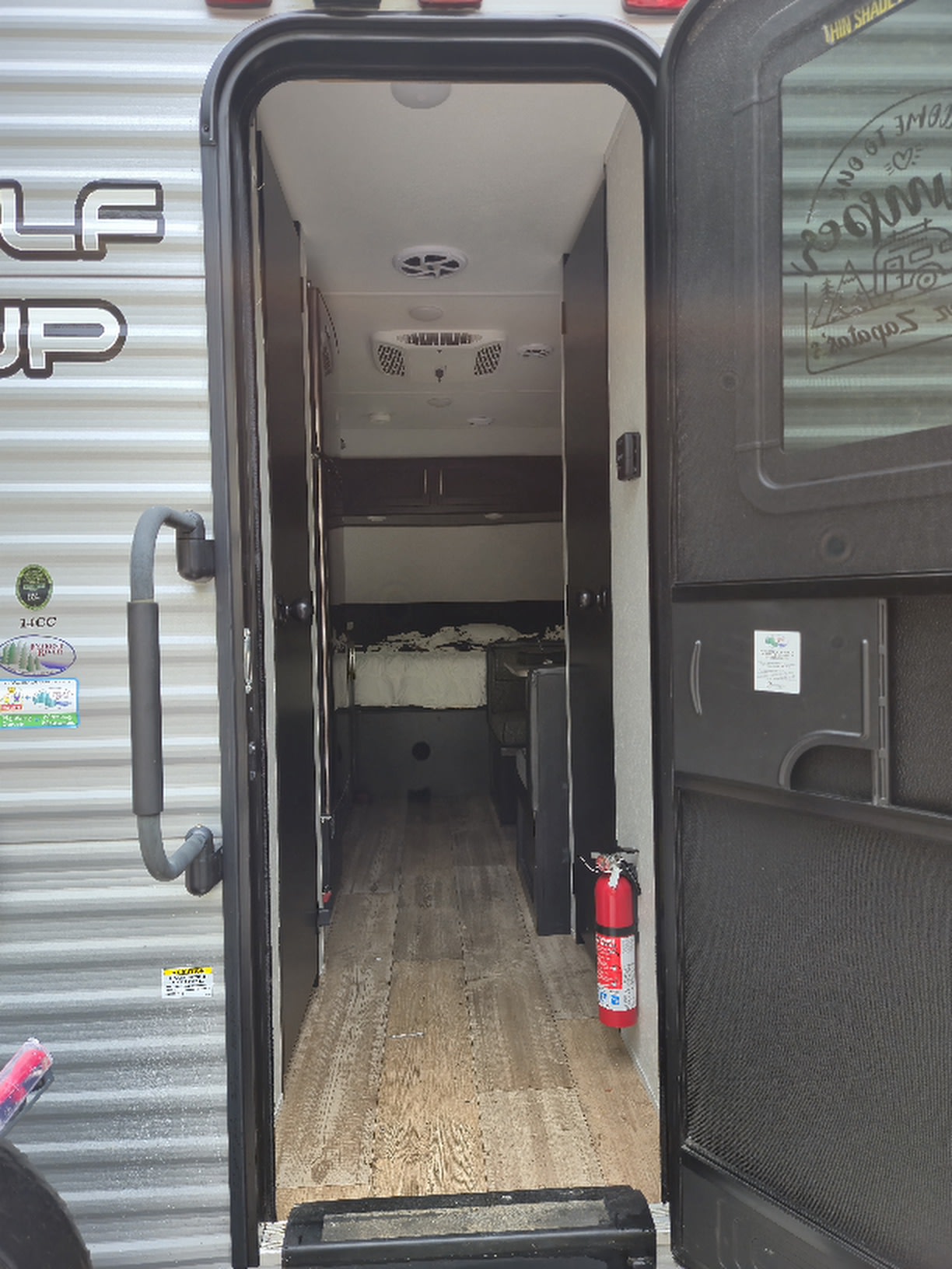 Inside an RV rental: View of the narrow interior hallway, wood-look flooring, bunk beds, & fire extinguisher, ready for travel.. Forest River Cherokee Wolf Pup 2021