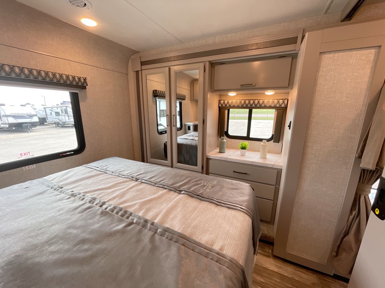 Discover this cozy RV rental bedroom. Features a comfortable bed, mirrored wardrobe, & window views, perfect for your next camping trip.. Thor Geneva 2024