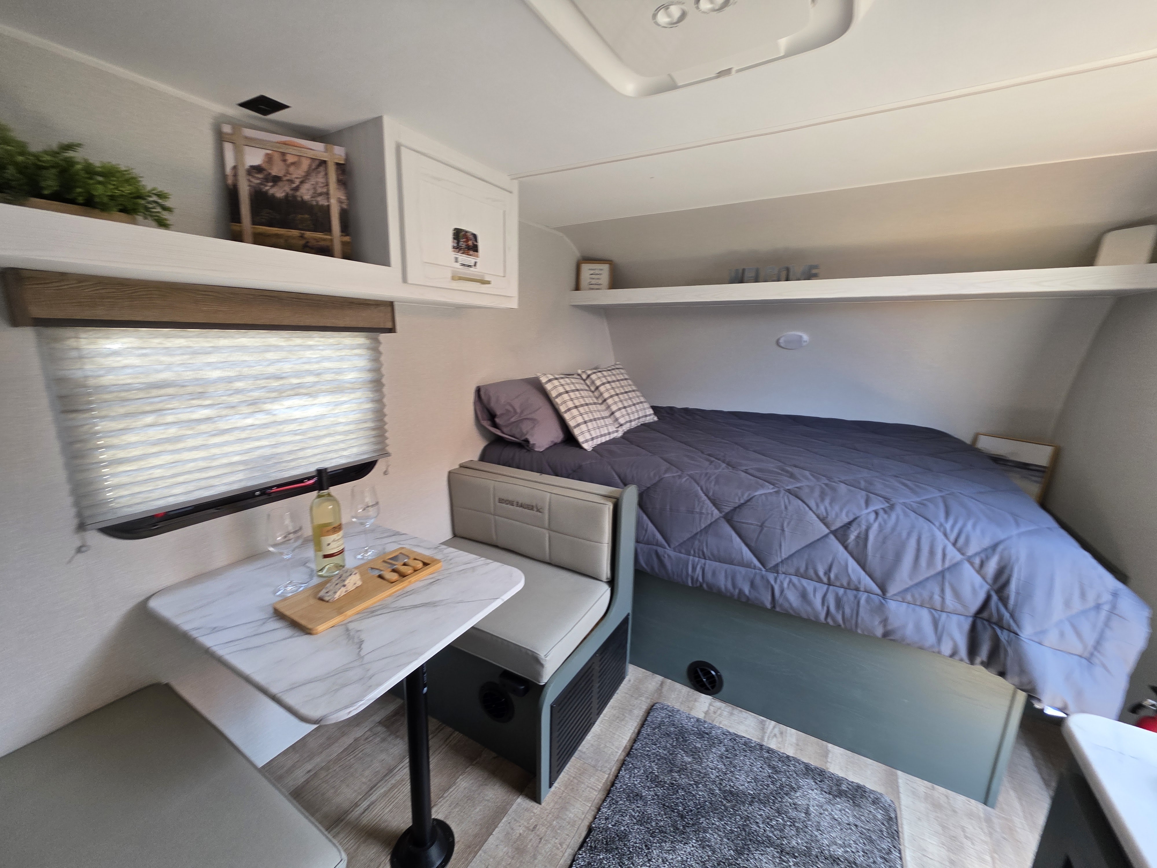 Step inside this cozy RV rental! A comfy bed, dining table with wine, and ample storage create a perfect travel retreat.. Heartland Eddie Bauer 2025