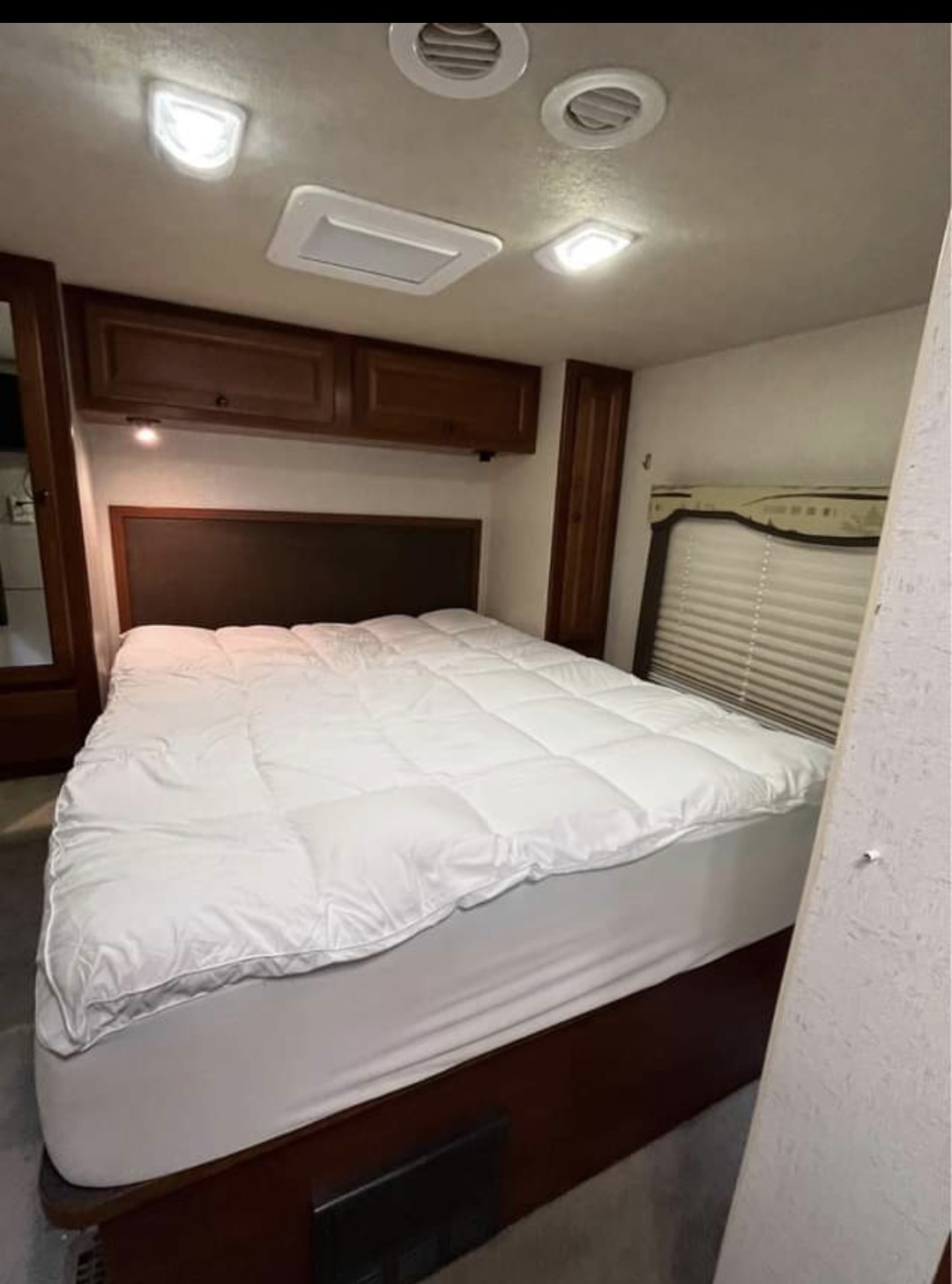RV rental bedroom: comfortable bed with white comforter, overhead storage, and bright interior lighting.. Tioga Tioga Motorhome 2009