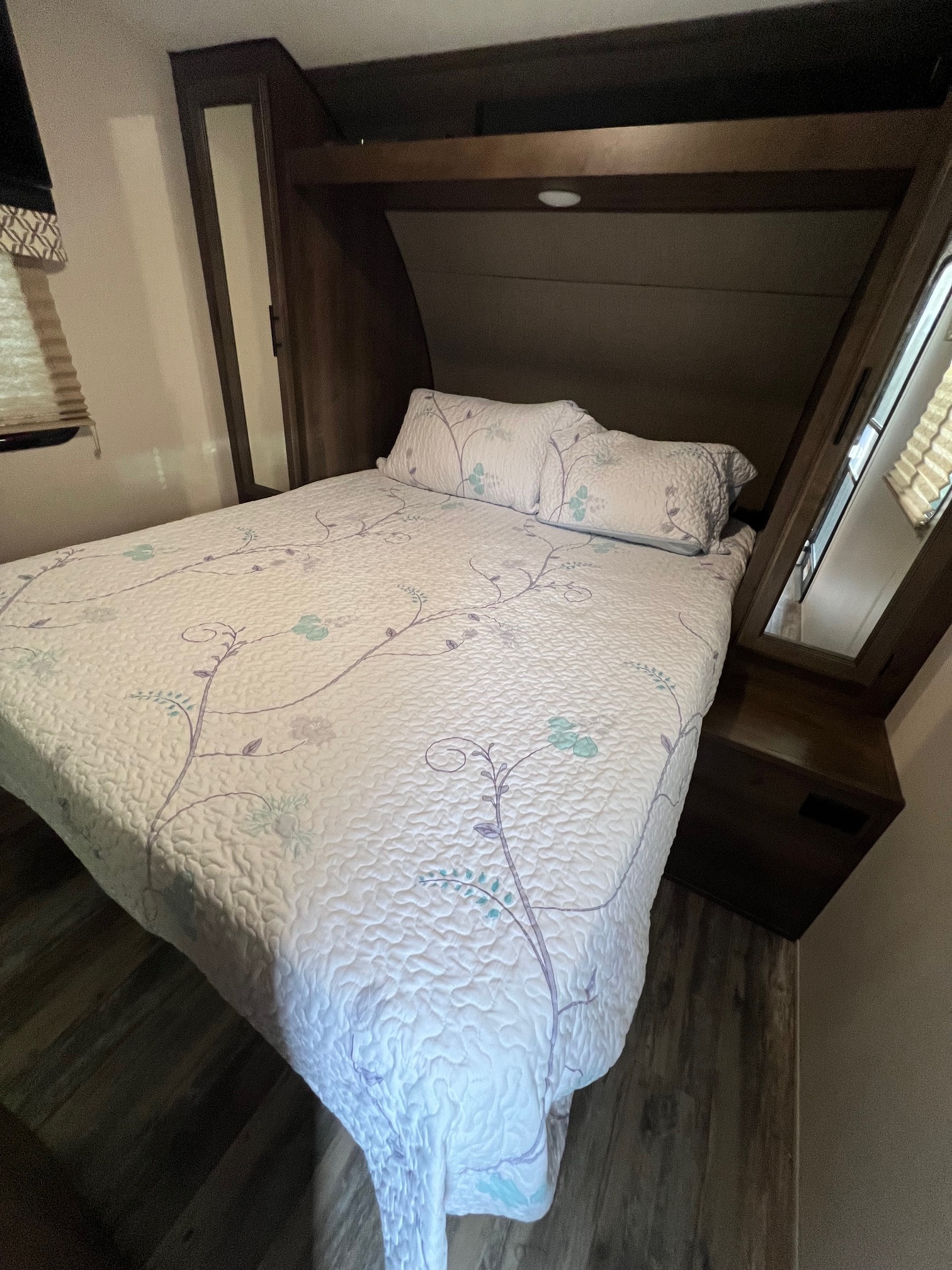 RV rental bedroom: cozy bed with floral quilted comforter, built-in cabinetry, and window view, ideal for travel.. KZ Connect RLK 24 2019