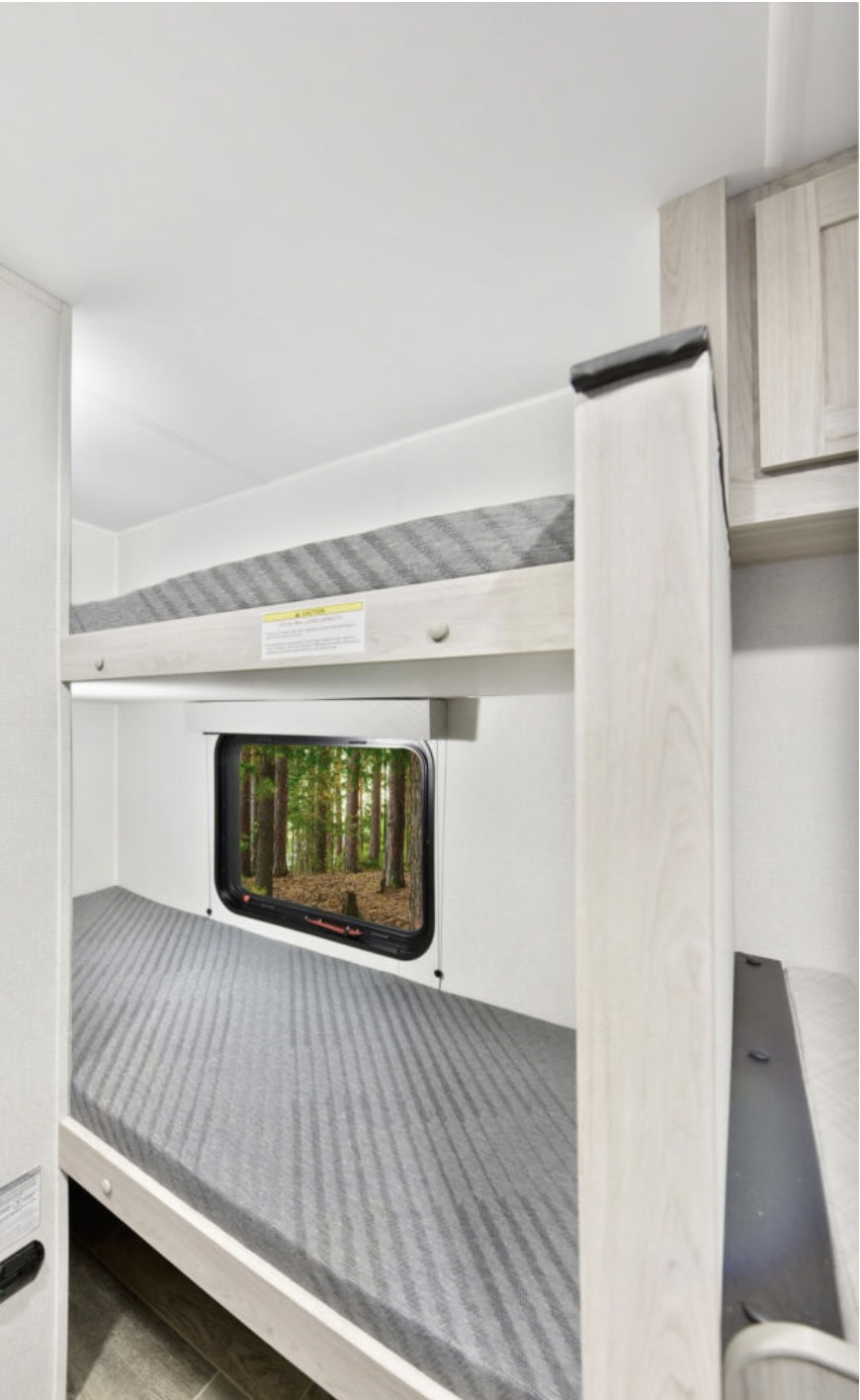 RV rental: Cozy bunk beds with grey mattresses inside, offering a scenic forest view from the lower window. Ideal for campers.. Heartland Pioneer 2025
