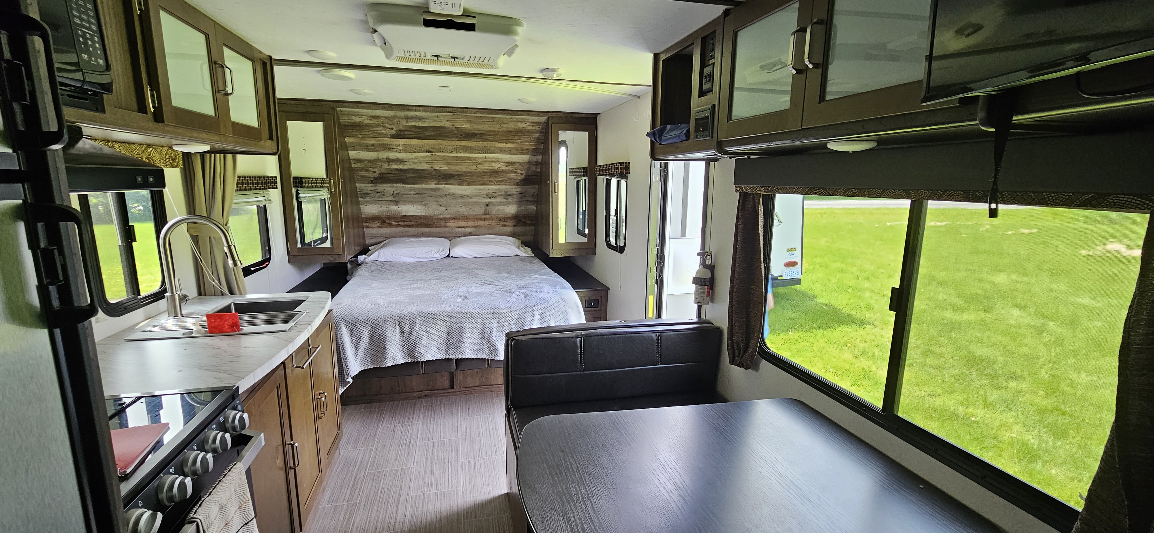 RV rental interior showing a fully equipped kitchen, comfortable bed, and dining booth overlooking nature.. Keystone Passport 2019