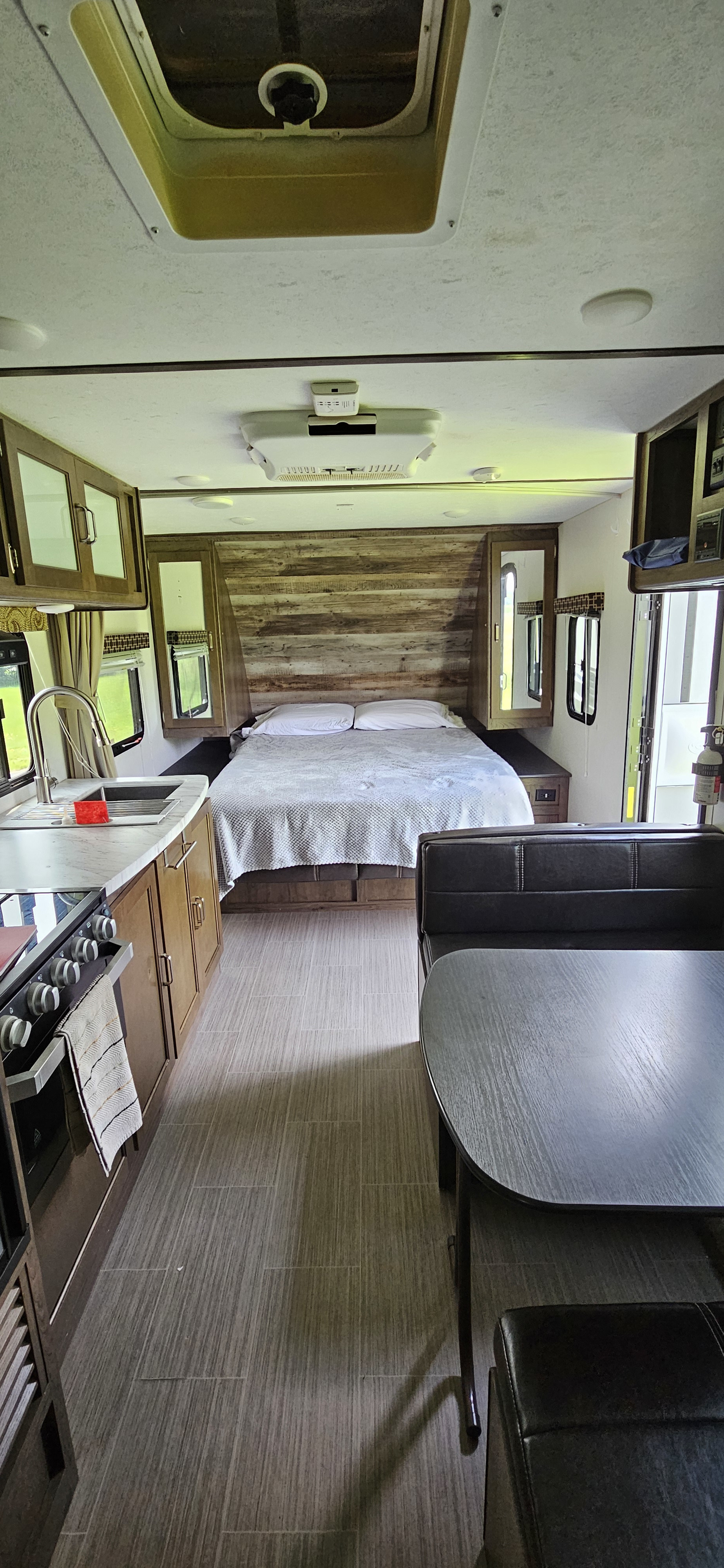 Cozy RV rental interior featuring a comfortable bed, full kitchen with sink and stove, and a dining booth.. Keystone Passport 2019