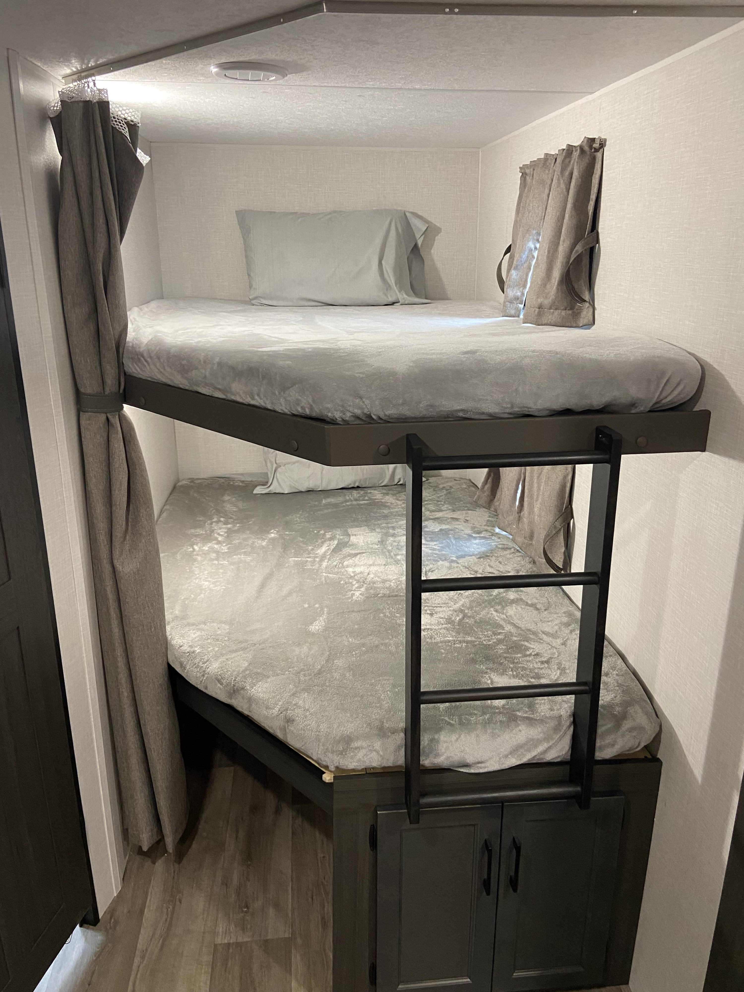 Cozy RV rental sleeping space with gray bunk beds, privacy curtains, and convenient ladder access.. Venture Rv Sporttrek 2026