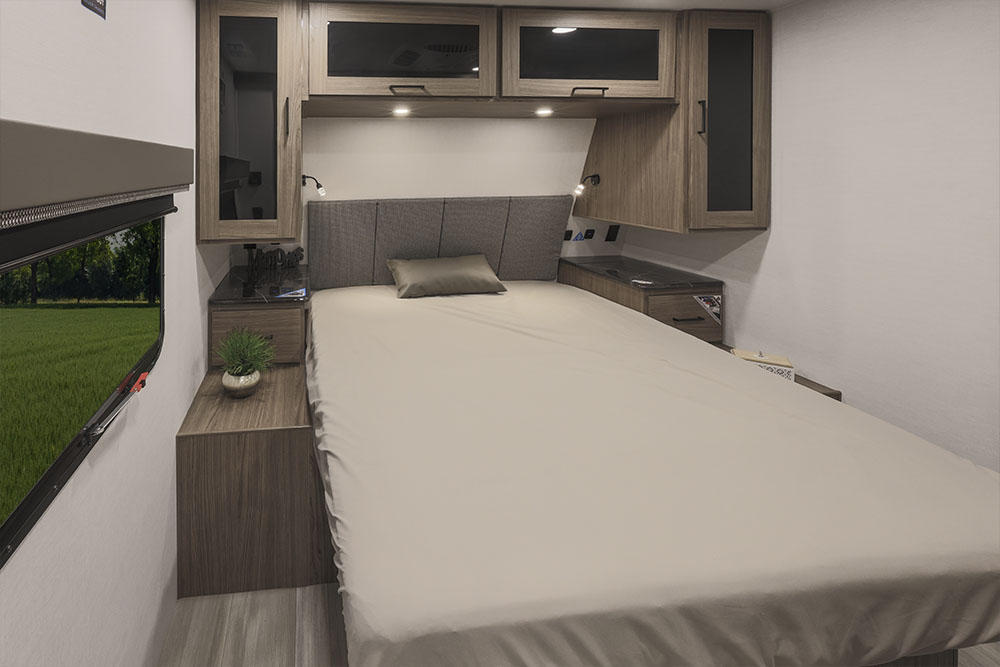 Comfortable RV rental bedroom interior with queen bed, overhead cabinets, and a scenic window view. Perfect for travel.. Alliance Delta 281bh 2024