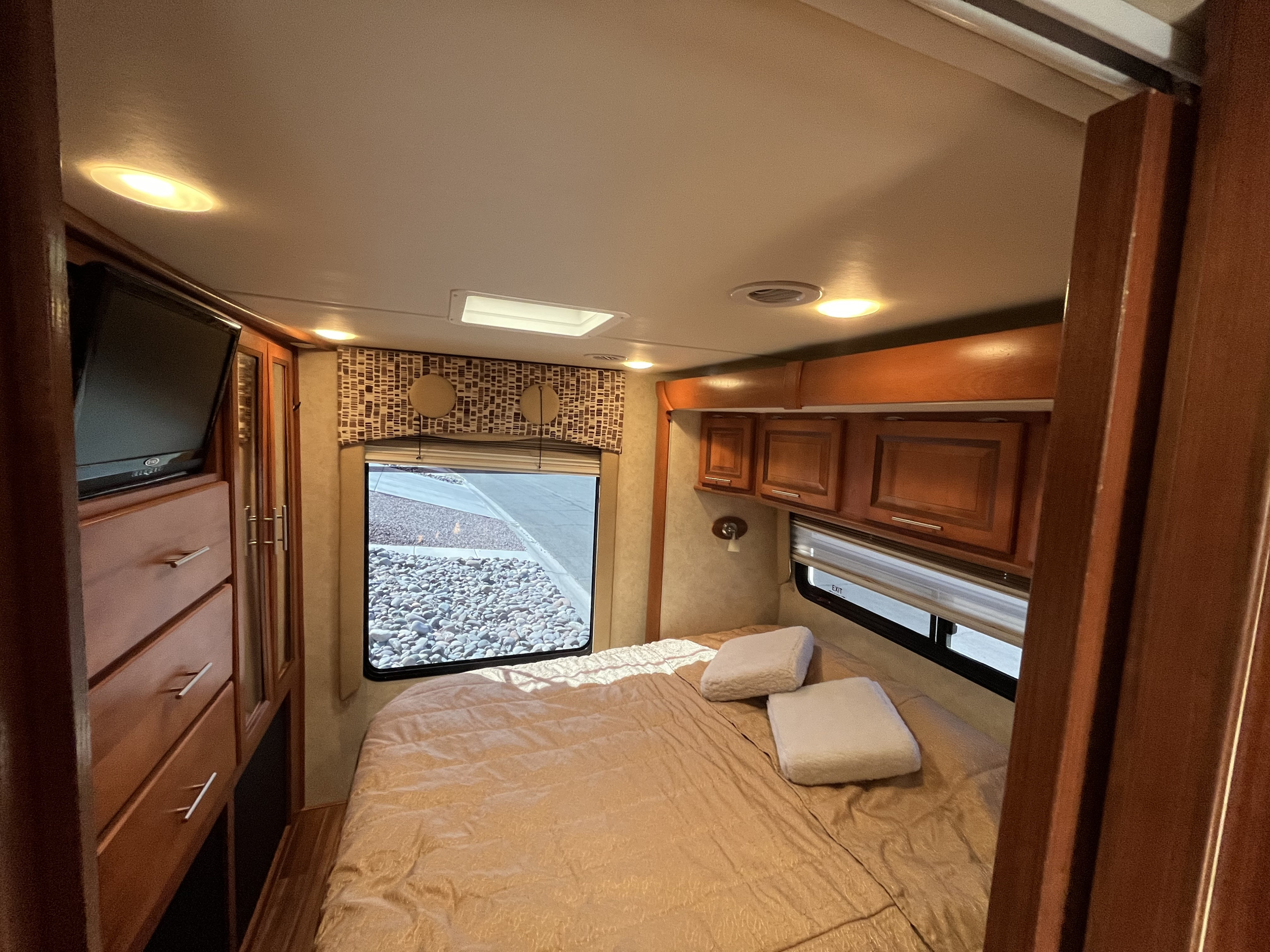 RV rental bedroom interior, featuring a bed, TV, window, and storage. Ideal for comfortable travel.. Forest River Coachmen Concord 2013