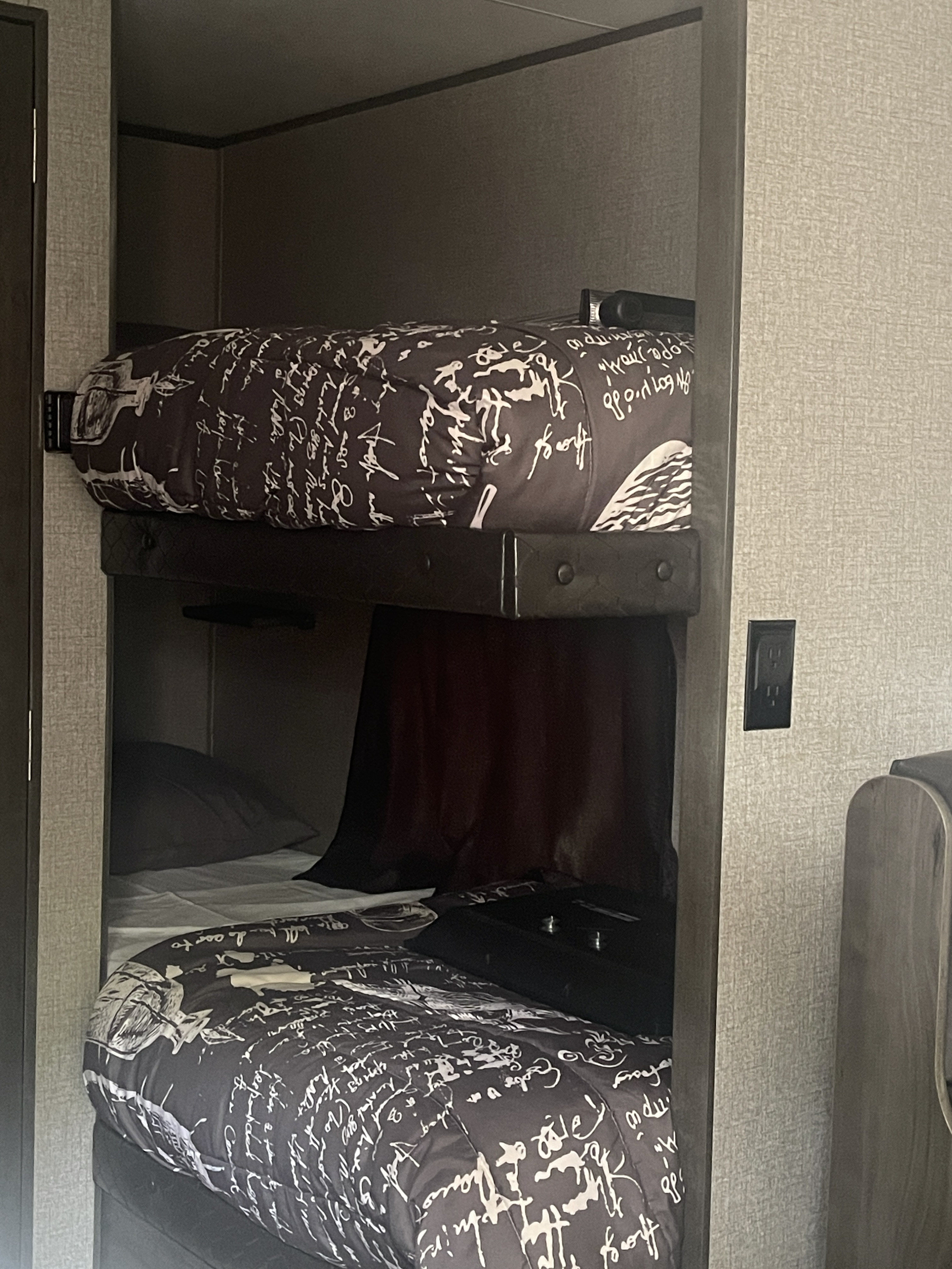 Compact bunk beds inside an RV rental. The top bunk features patterned bedding, and the bottom has white sheets.. Jayco Jay Flight SLX 2021