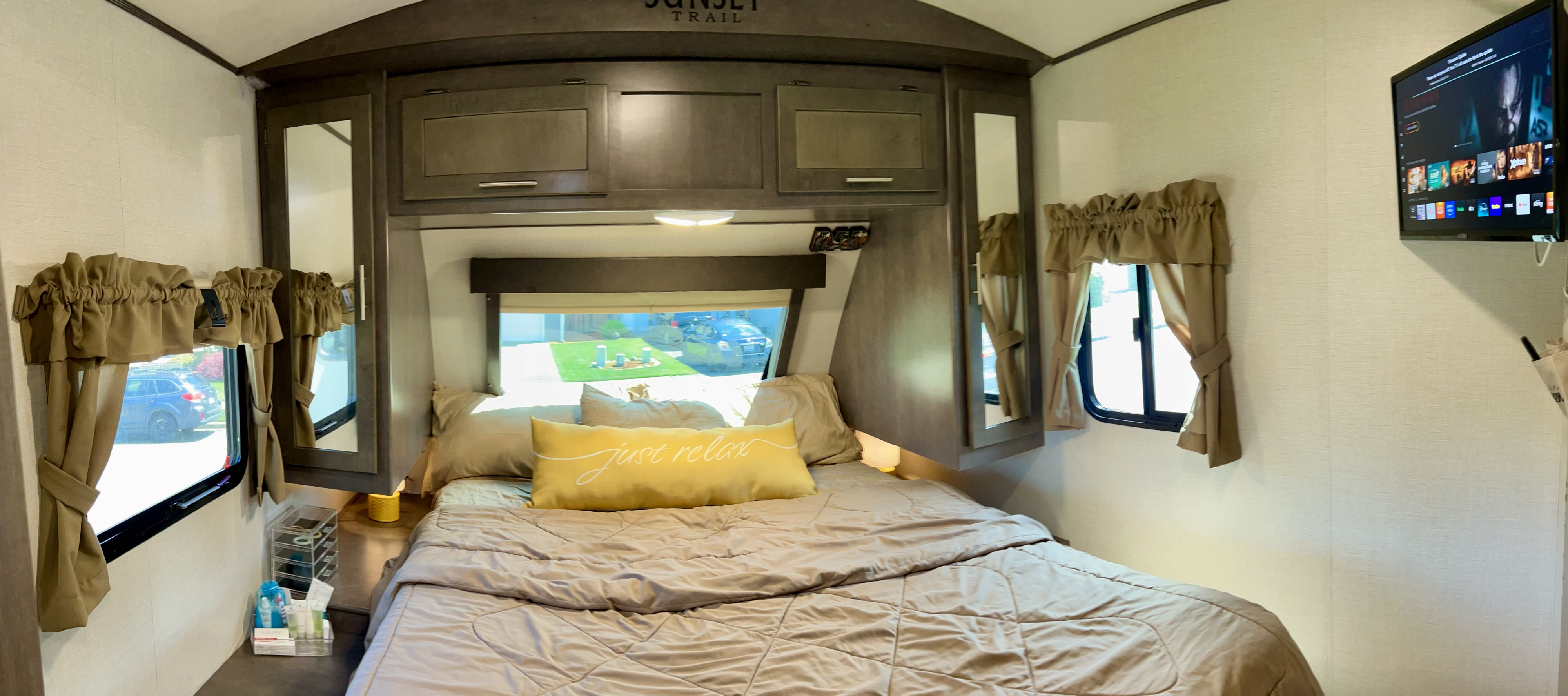Comfortable RV rental bedroom with bed, overhead storage, windows, and TV. Ideal for travel.. Crossroads RV Sunset Trail Grand Reserve 2018