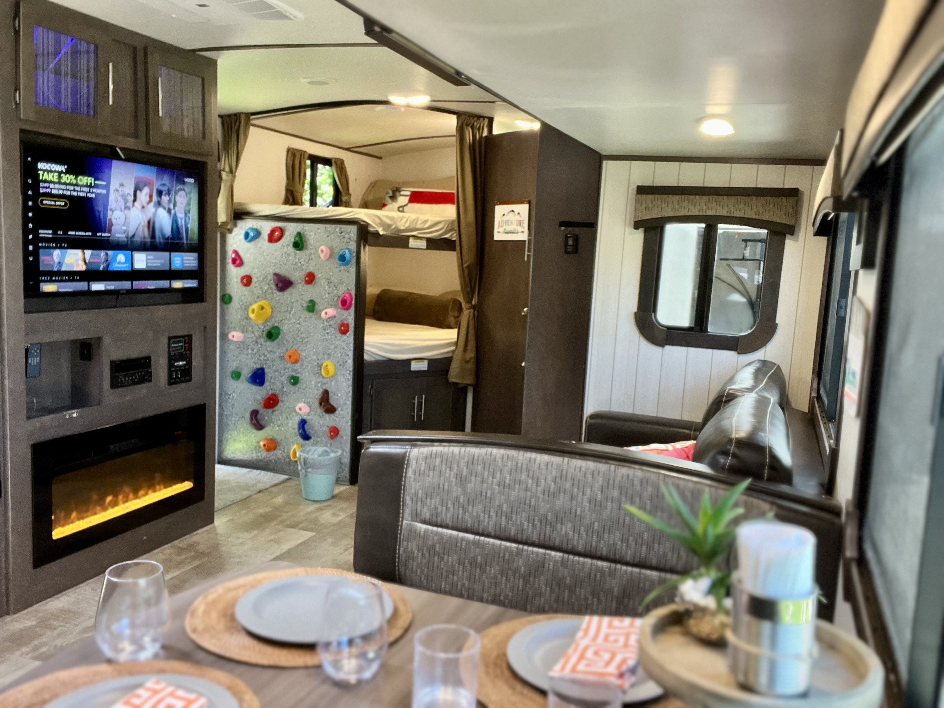 Spacious RV rental interior with fun climbing wall, bunk beds, TV/fireplace, and dining area. Ideal for family adventures.. Crossroads RV Sunset Trail Grand Reserve 2018
