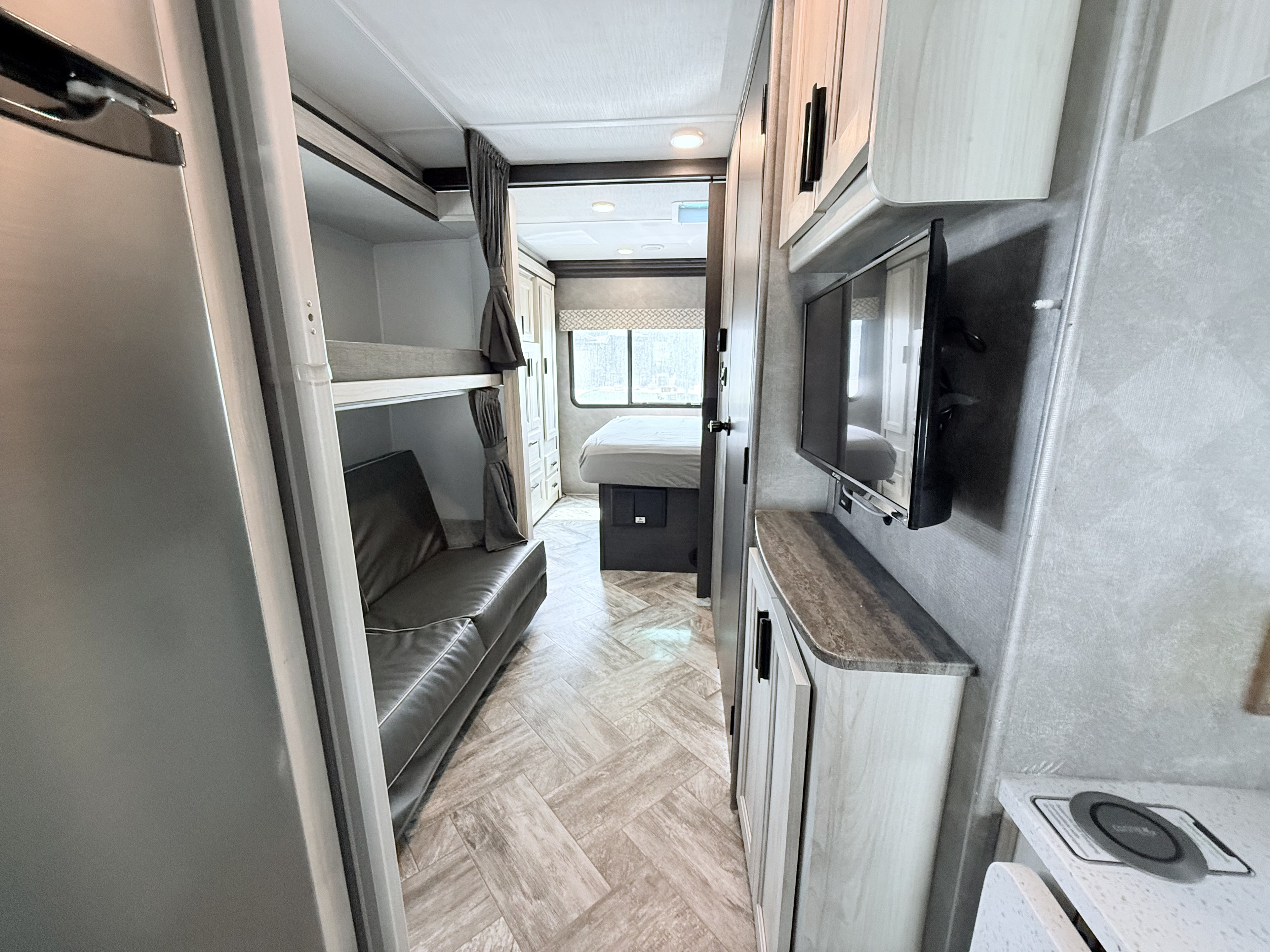 RV rental interior: view from the fridge to bunk beds, a sofa, and the main bedroom with an entertainment area.. Forest River Forester 2023