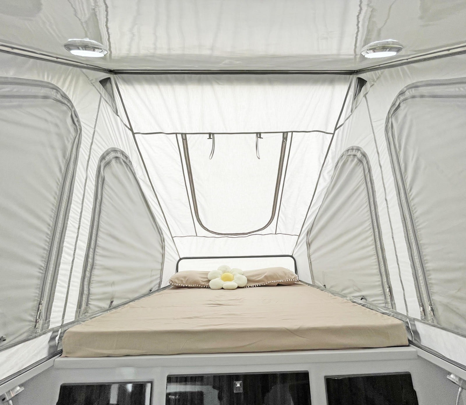 Cozy interior of a rooftop tent with a comfy bed, perfect for your RV rental adventure. Lights & windows visible.. Zoomies Campers Spirit 2025