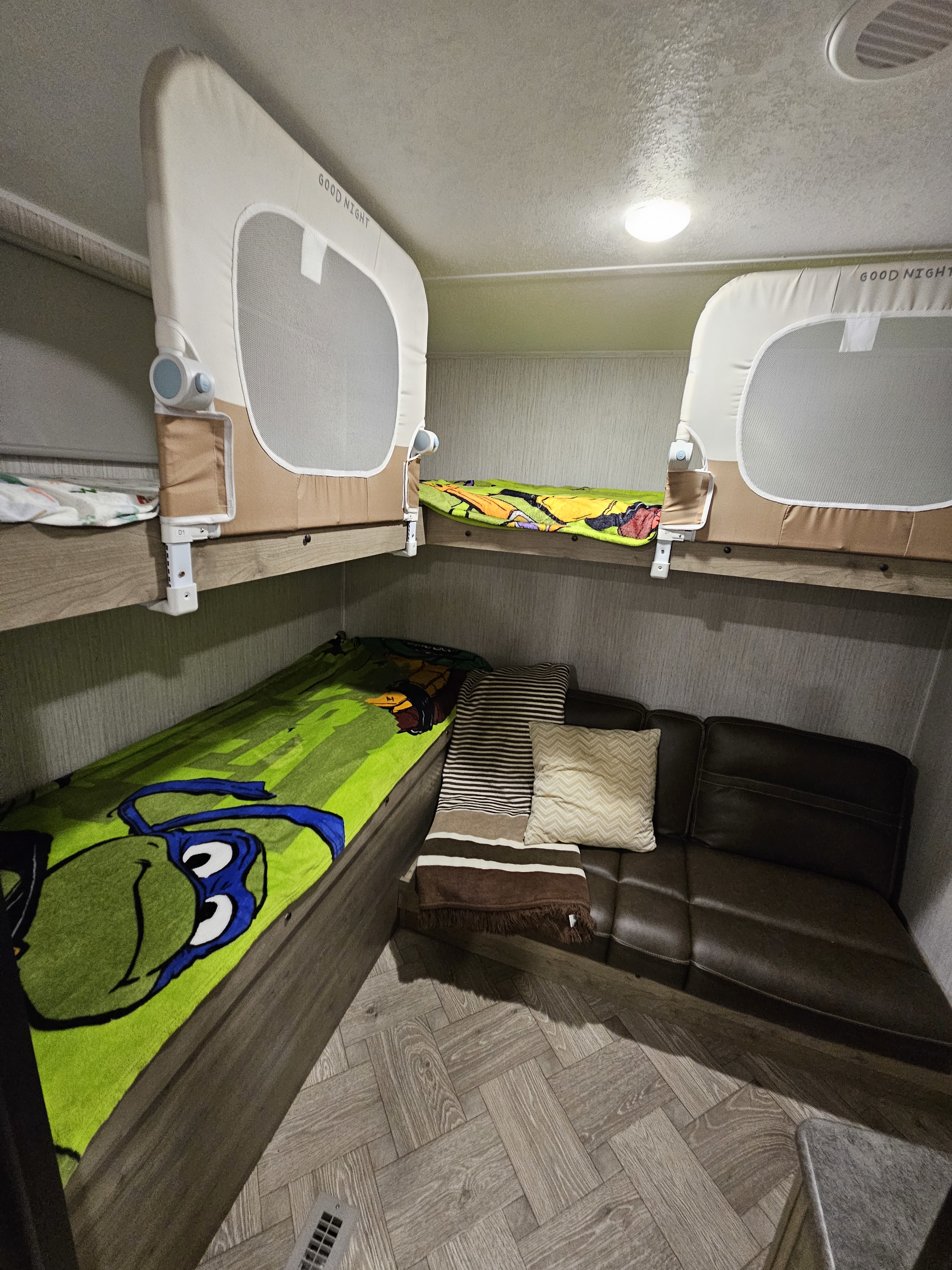 RV rental: A cozy interior featuring bunk beds with safety rails, a TMNT blanket, and a brown leather sofa.. Forest River Palomino Puma 2022