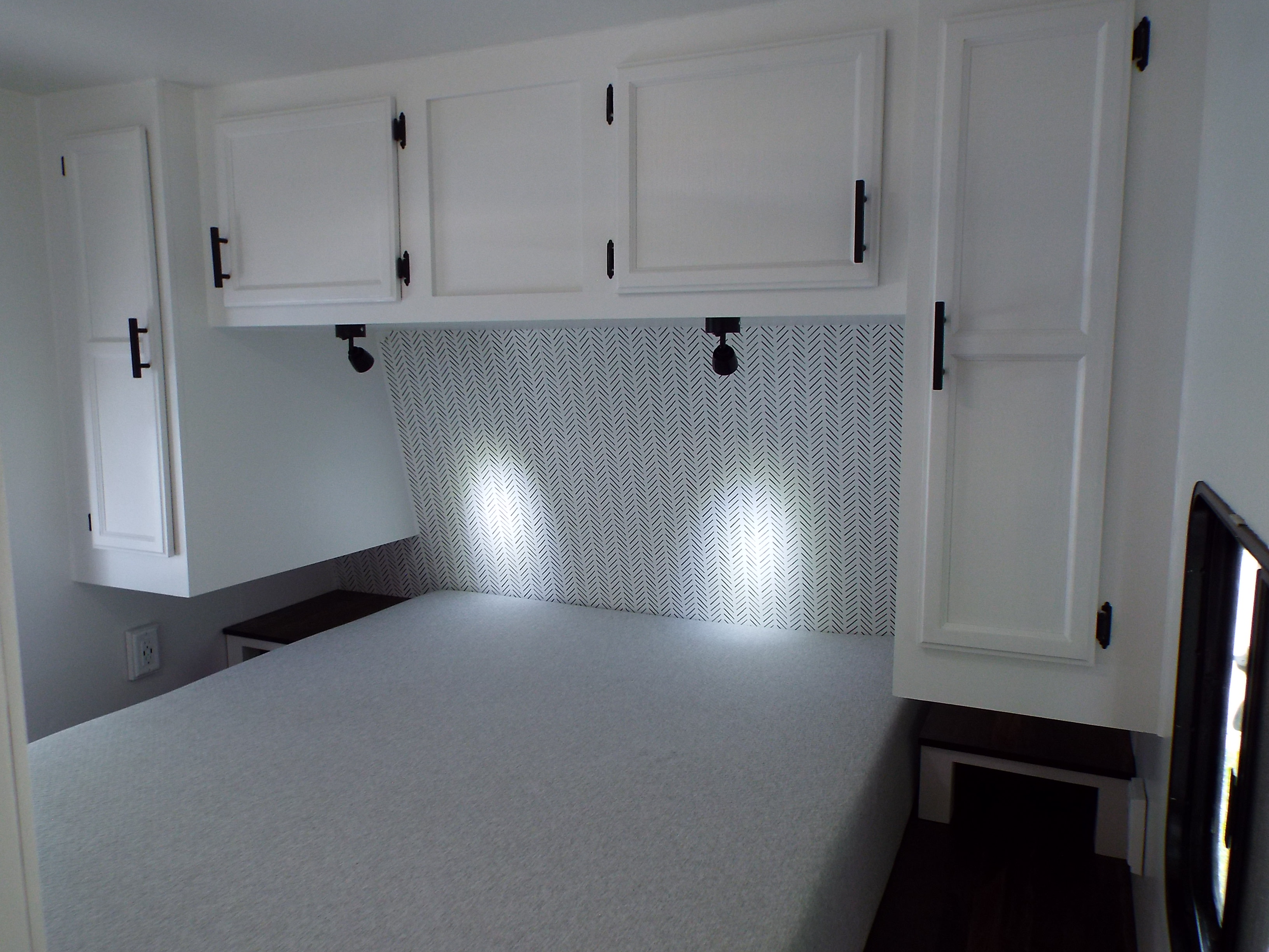 RV rental interior showing a clean bedroom with white cabinets, herringbone headboard, and a cozy bed.. Jayco Jay Flight 2011