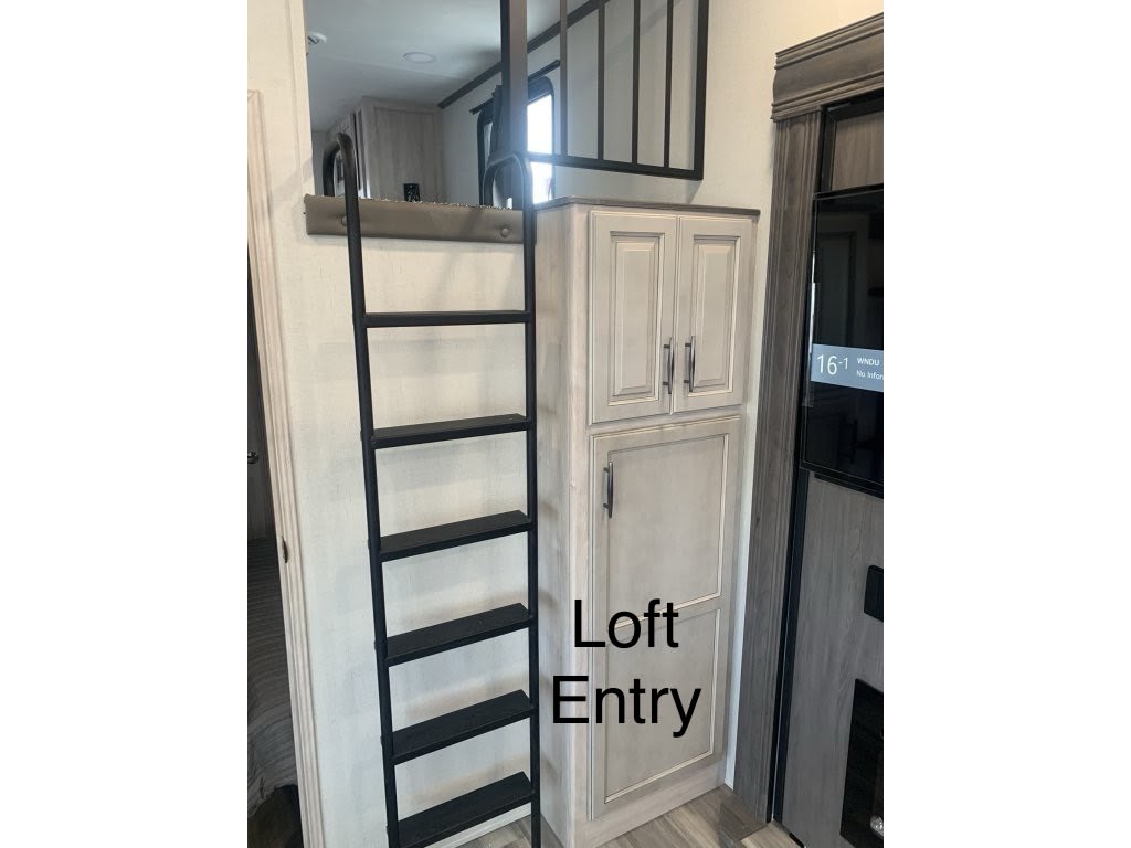 RV rental: See a compact interior featuring a black loft ladder, light cabinets, and a built-in entertainment center.. Forest River Sandpiper 2024