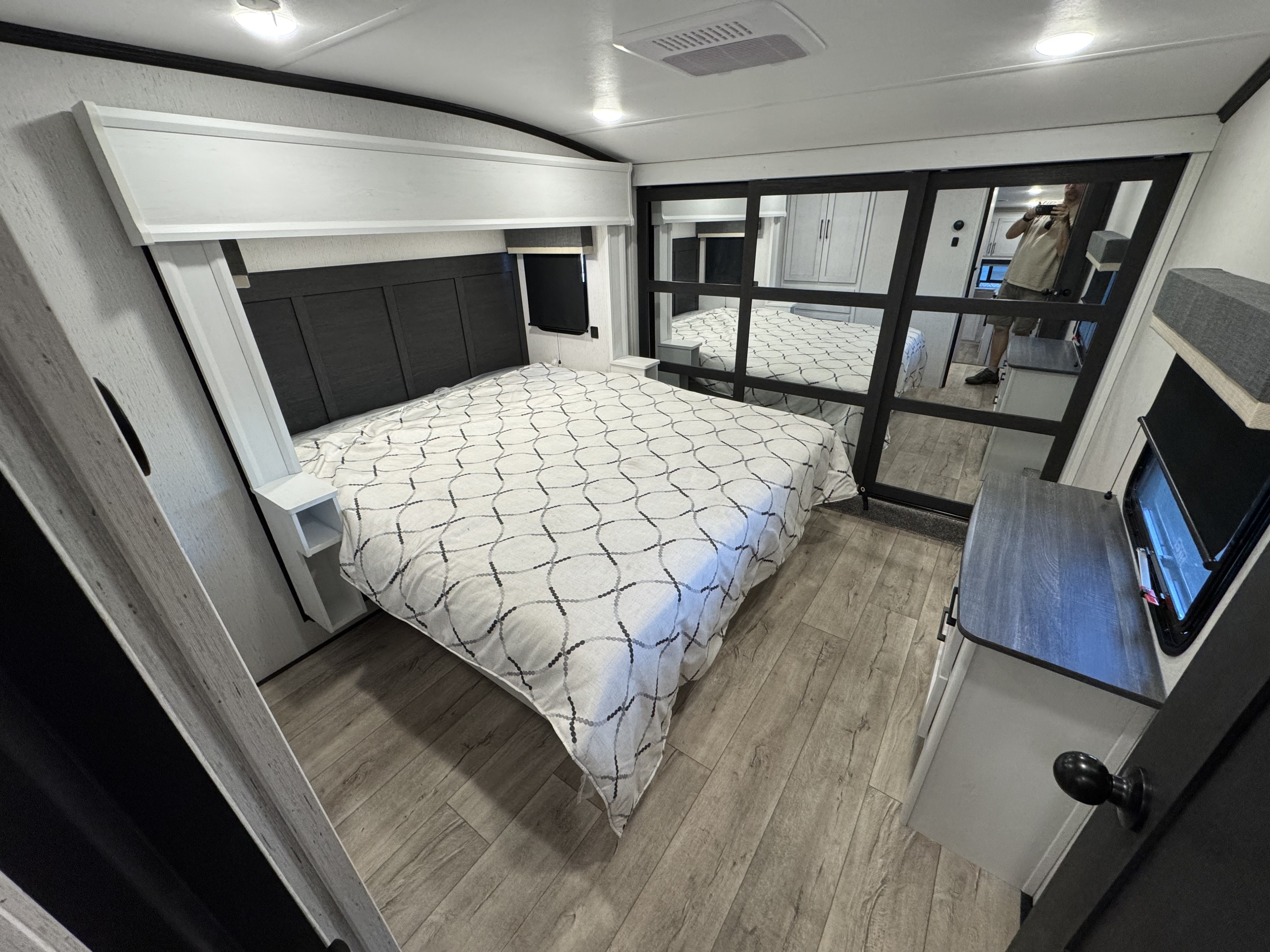 Inside an RV rental: a modern bedroom featuring a comfortable bed, built-in nightstands, and mirrored closet doors.. Dutchmen Astoria 260RK 2025