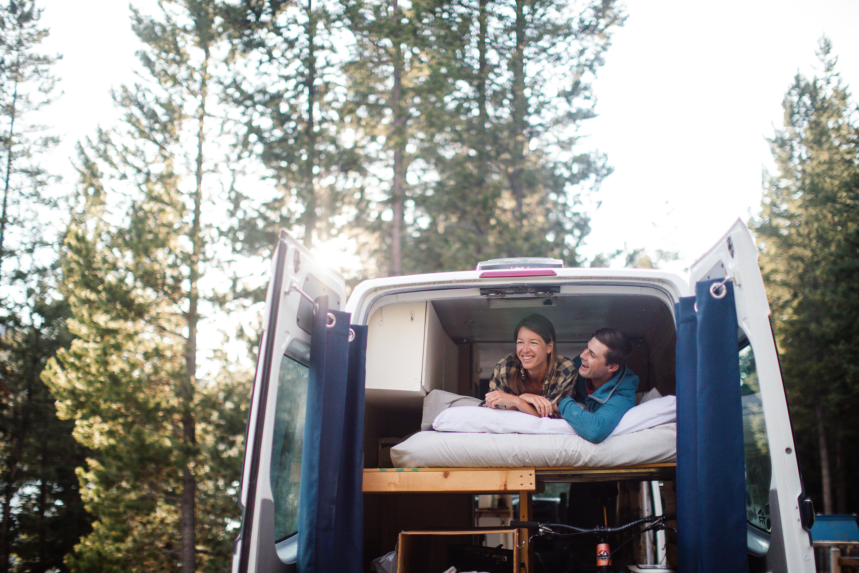 Happy couple enjoying their RV rental adventure, relaxing in a custom camper van parked in a sunny forest.. Dodge Sprinter 2500 170ext 2008