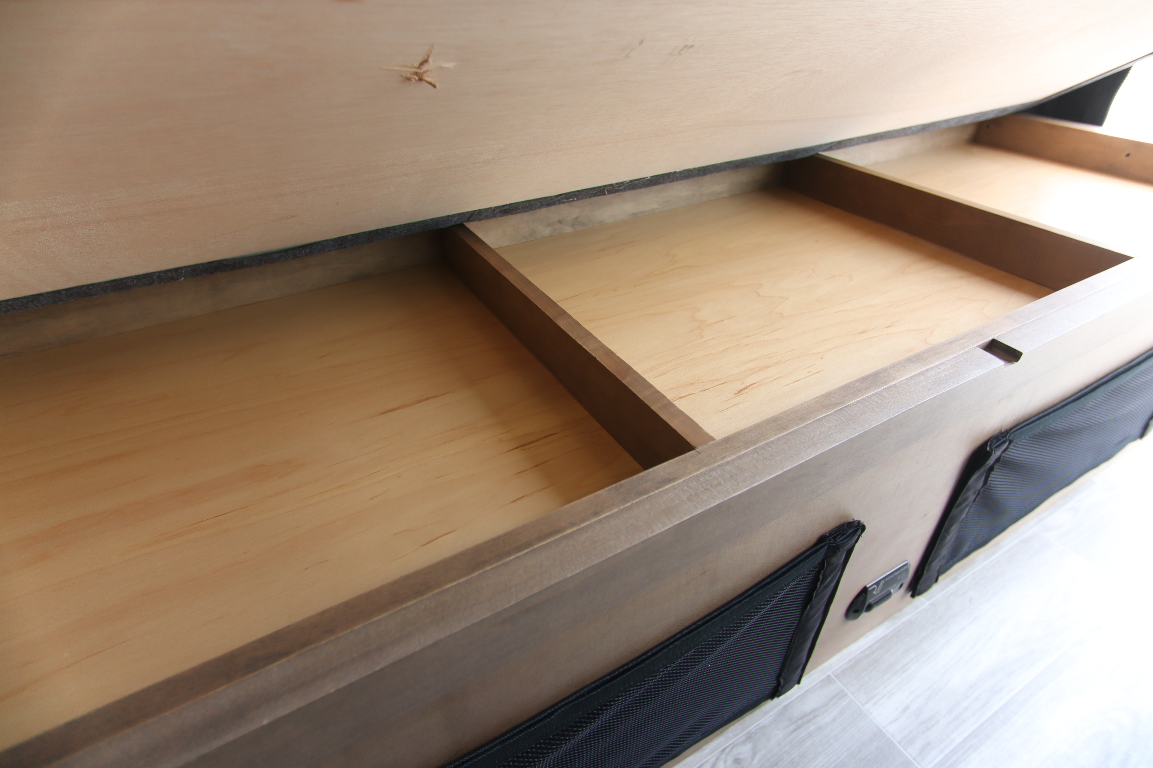 RV rental under-bed storage: Open wooden compartment with divider, showcasing efficient space for organized travel.. Tiffin Motorhomes Cahaba 2022