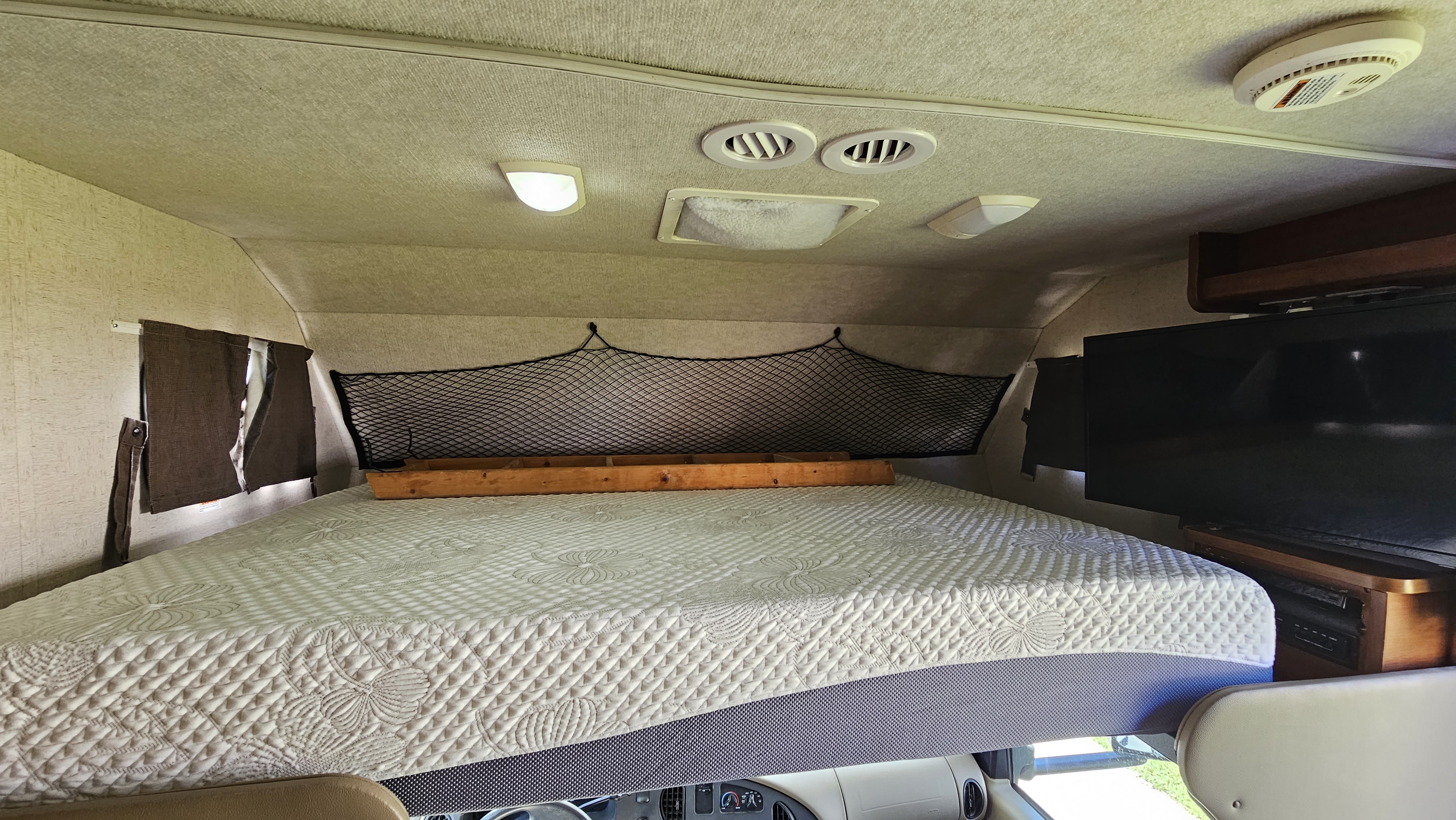 Cozy RV rental cab-over bunk with quilted mattress, safety net, lights, vents, and TV. Great for travel!. Tioga Ranger 2009