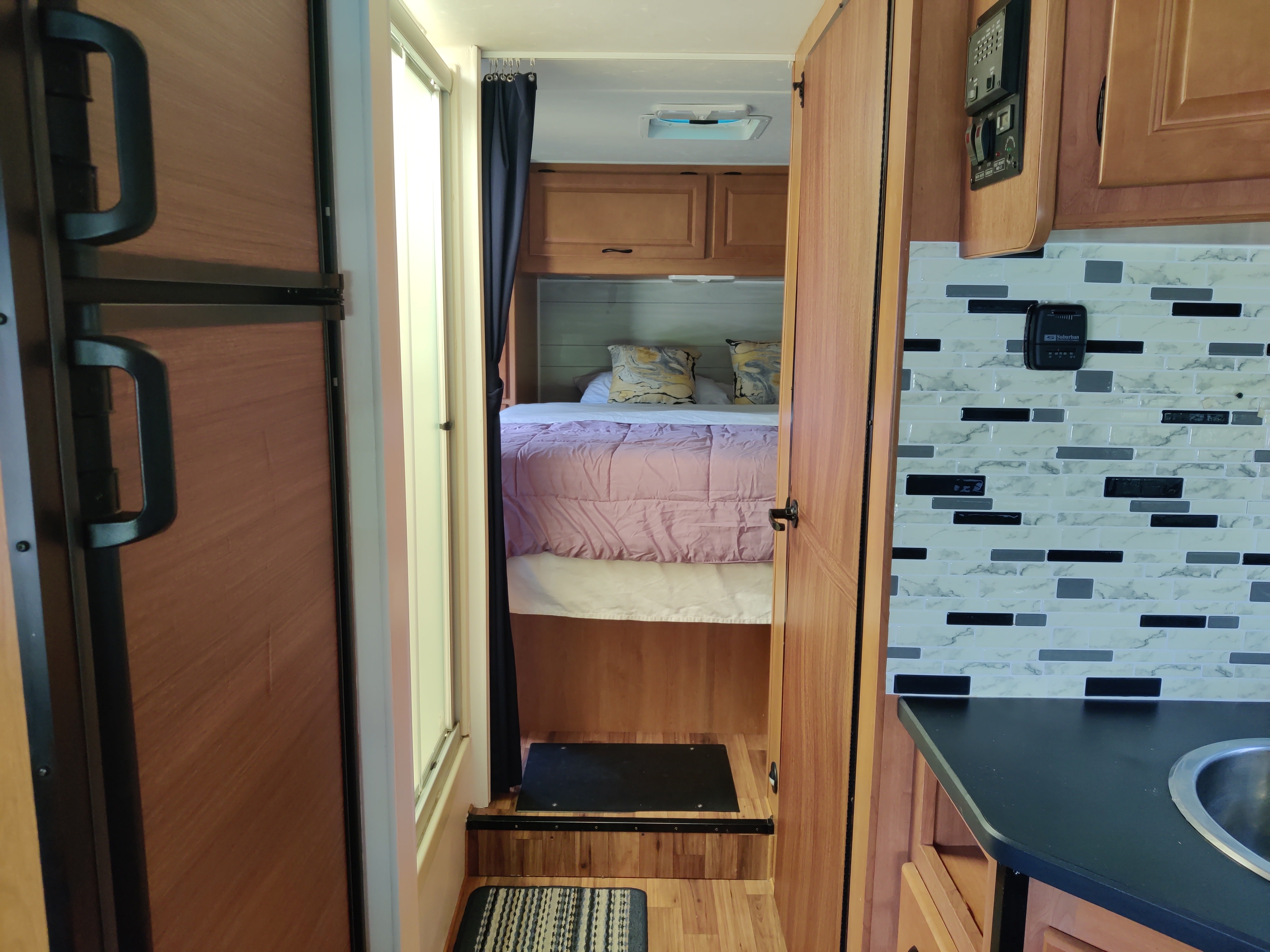 Explore this RV rental's interior, featuring a cozy bedroom area, a compact kitchen with sink & tile backsplash, and a refrigerator.. Thor Majestic 2015
