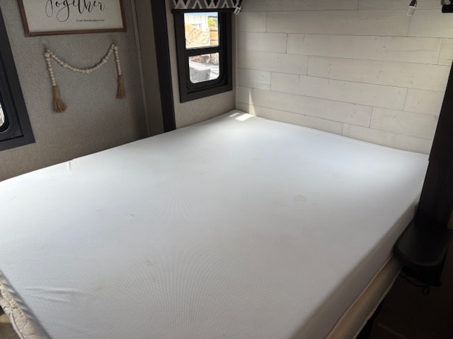 Clean **RV rental** bedroom interior features a white mattress, light wood walls, and windows.. Jayco Alante 2021