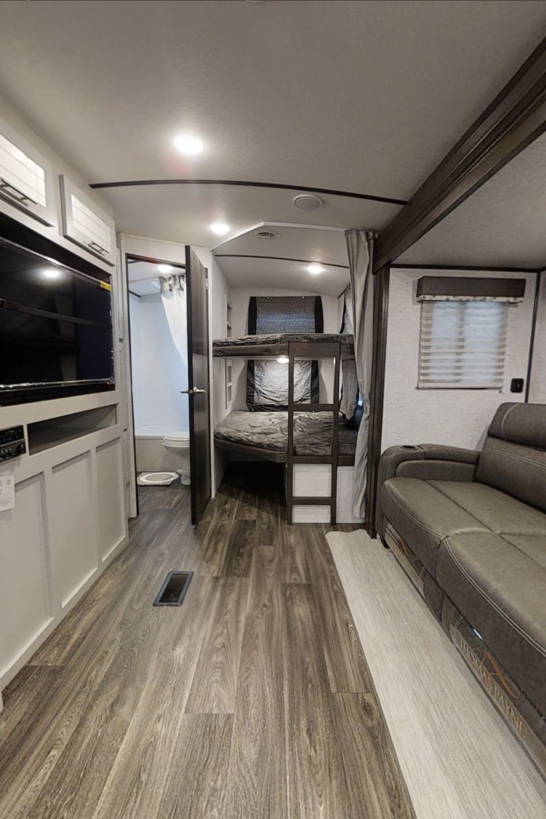 Explore this modern RV rental interior featuring a living area with sofa, bunk beds, and a full bathroom.. Keystone RV Bullet Ultra Lite 2021