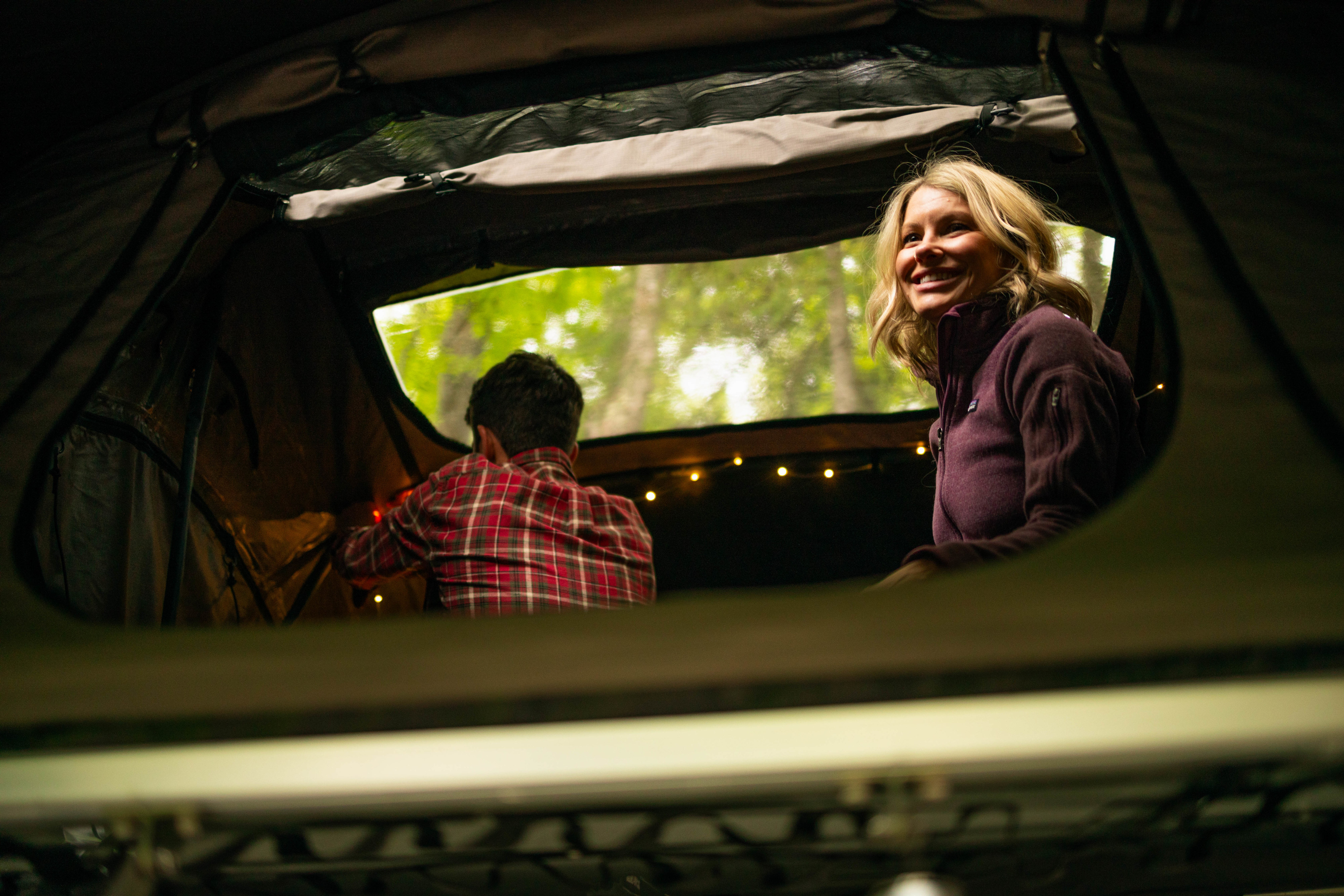 Couple relaxing in an RV rental, enjoying nature with cozy string lights. She smiles, he faces away.. 1C4PJXDN9RW109044 Other 2024