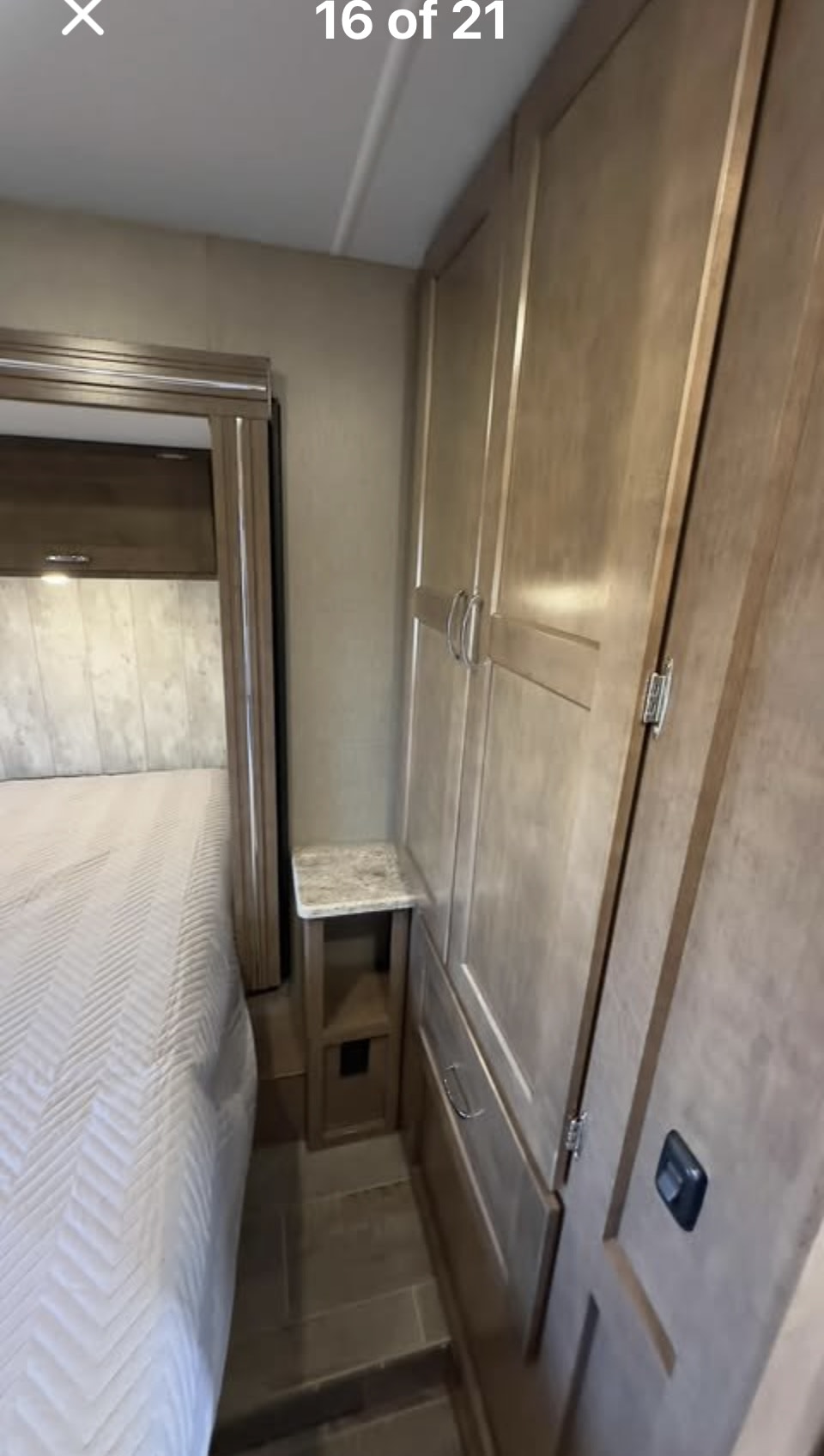 RV rental interior: A compact bedroom features a quilted bed, small nightstand, and built-in wardrobes.. Winnebago Outlook 2019