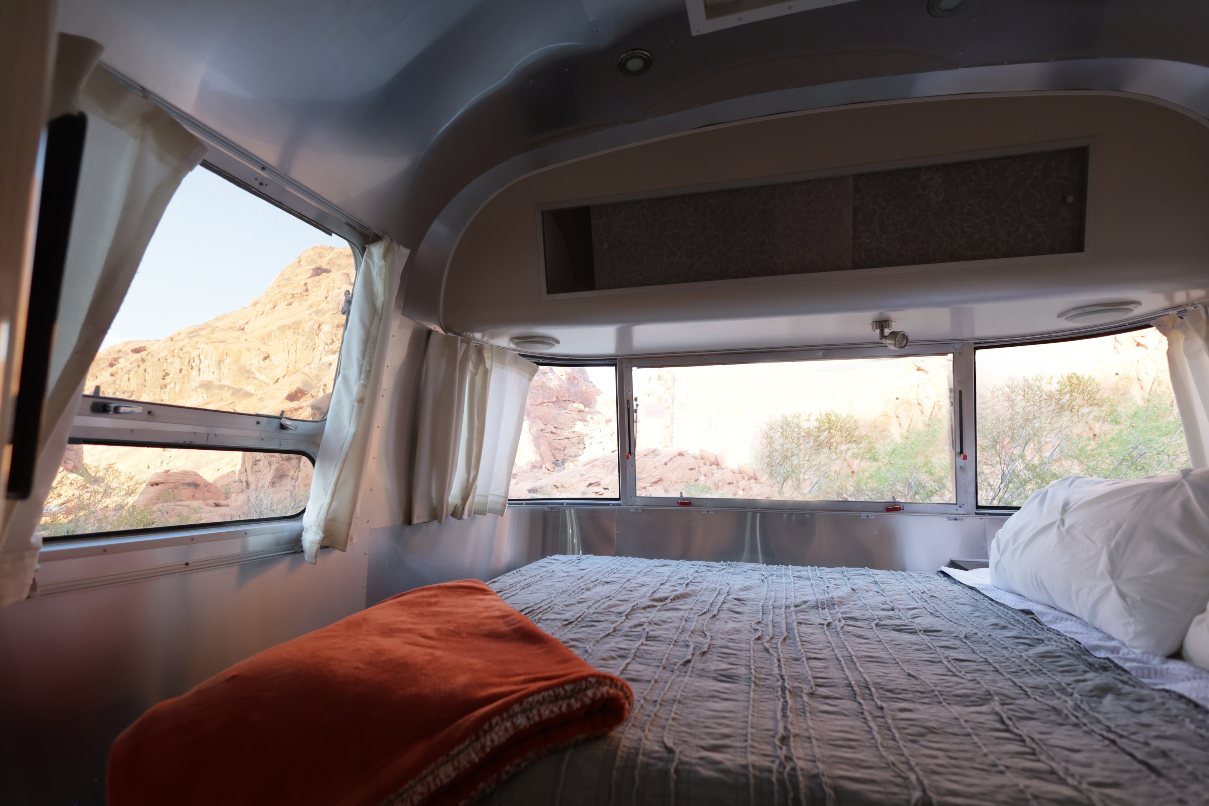 Comfortable RV rental interior with bed and stunning desert mountain views outside. Perfect for scenic travel.. Airstream International 2012