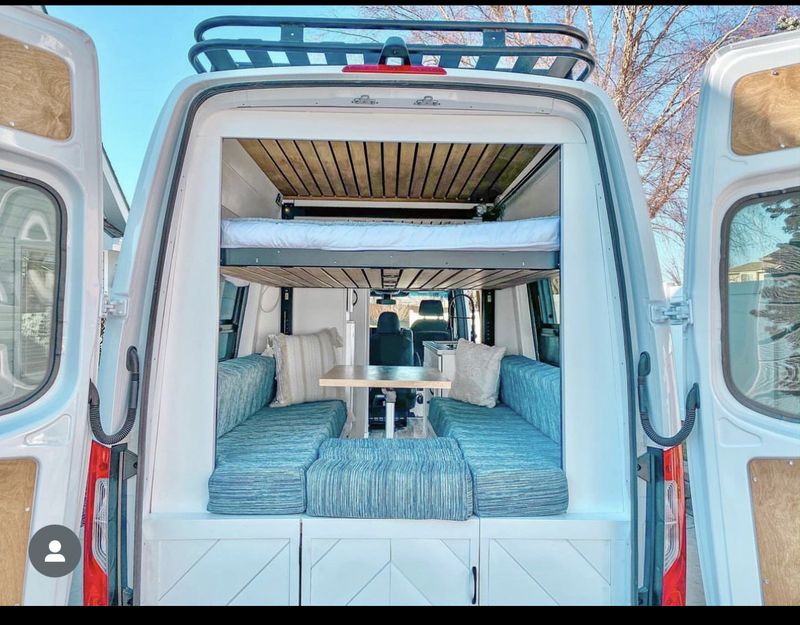 This custom camper van interior, perfect for rv rental, features a clever layout with an elevated bed over comfy seating and dining.. Custom Crafted Vans Family Van 2019