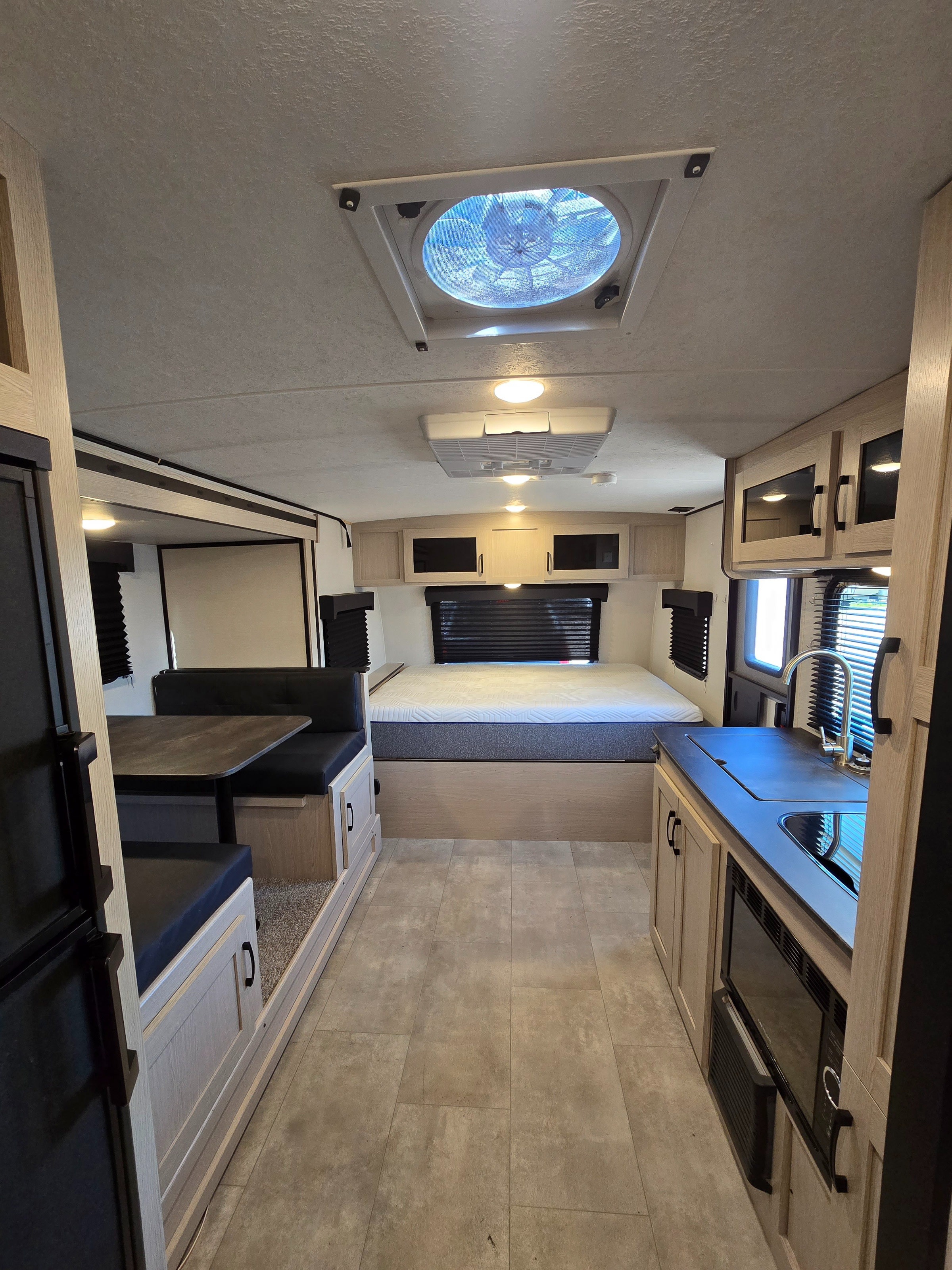 Spacious RV rental interior featuring a cozy bed, dinette, and functional kitchen with modern amenities.. Coachmen Apex Nano 2021