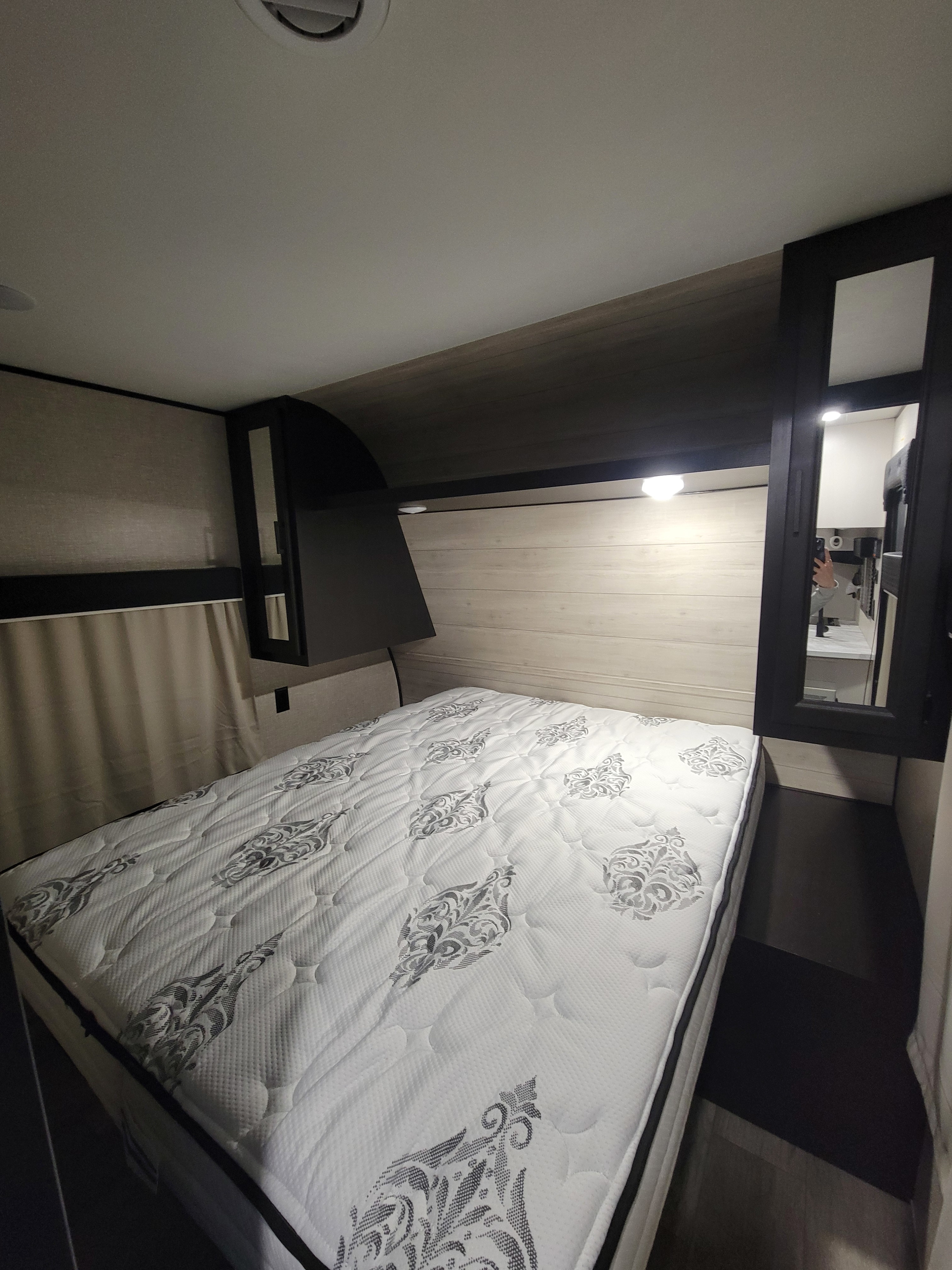 This inviting RV rental bedroom features a comfy bed with a patterned mattress, overhead storage, and a mirrored cabinet.. Jayco Jay Flight SLX 2022