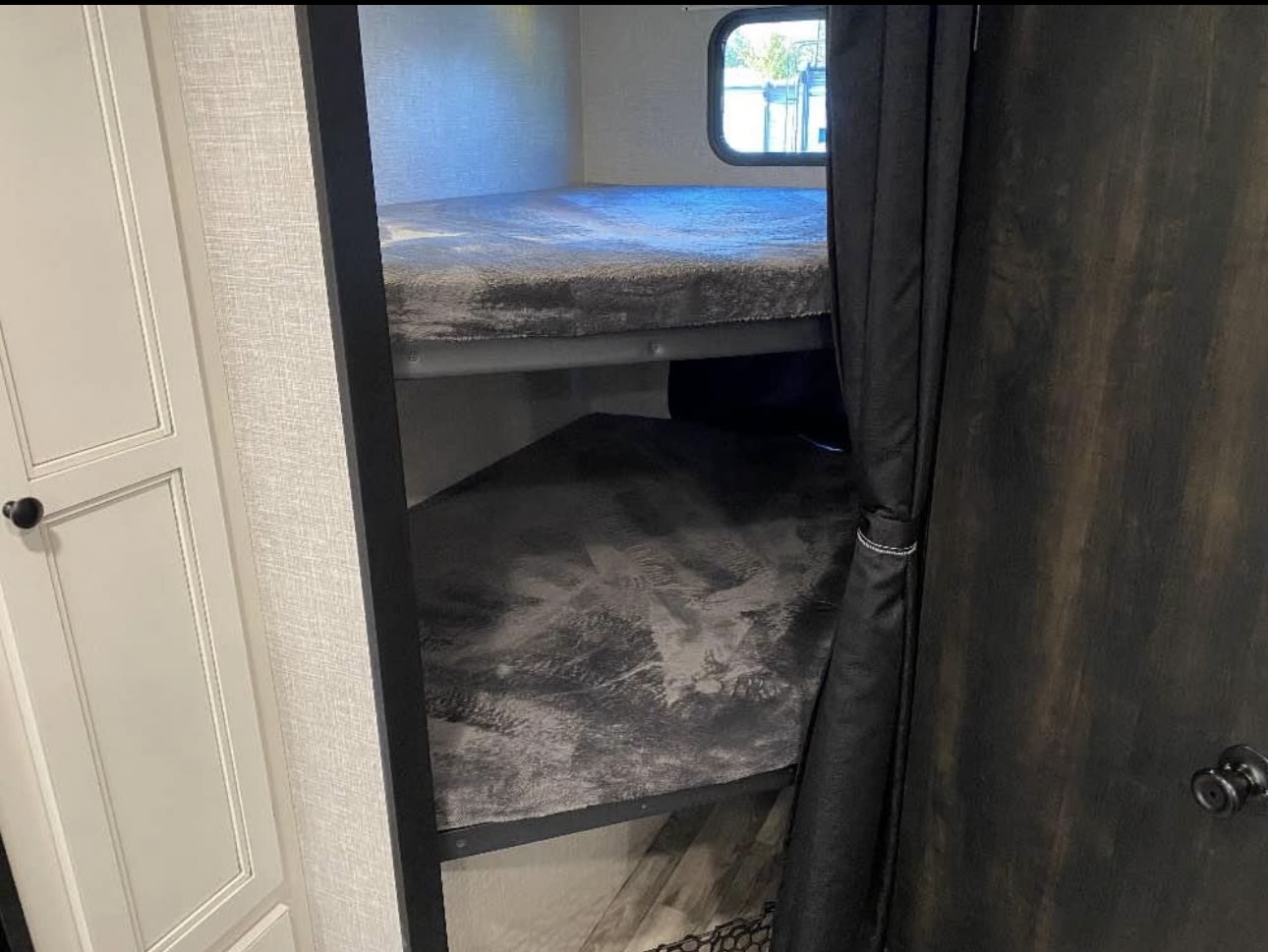 This RV rental features a cozy sleeping area with two bunk beds and privacy curtains.. Highland Ridge RV Range Lite 2023