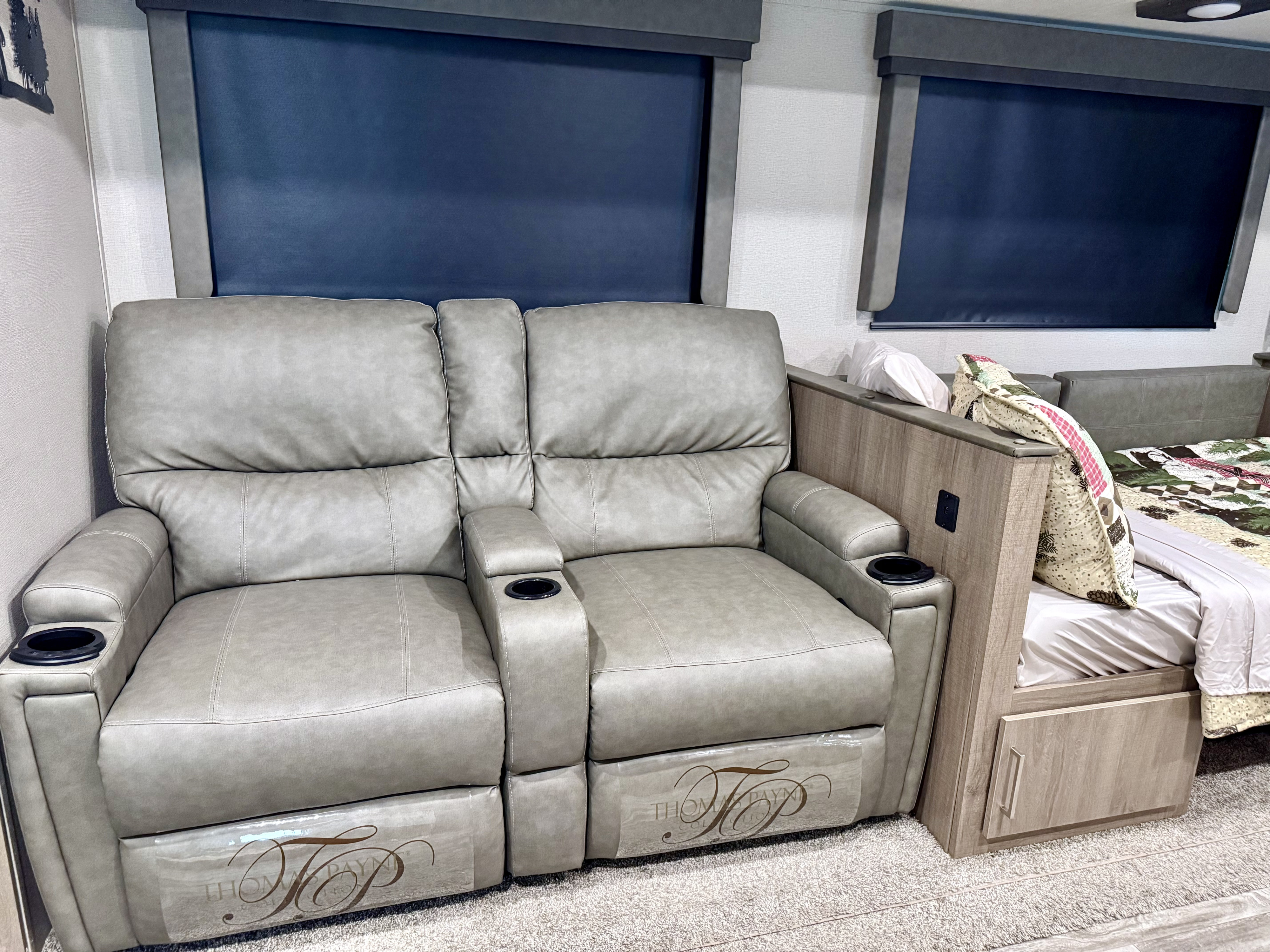 RV rental interior: two gray recliners with cup holders, dark window shades, and a cozy bed with storage.. Grand Design Imagine 2021
