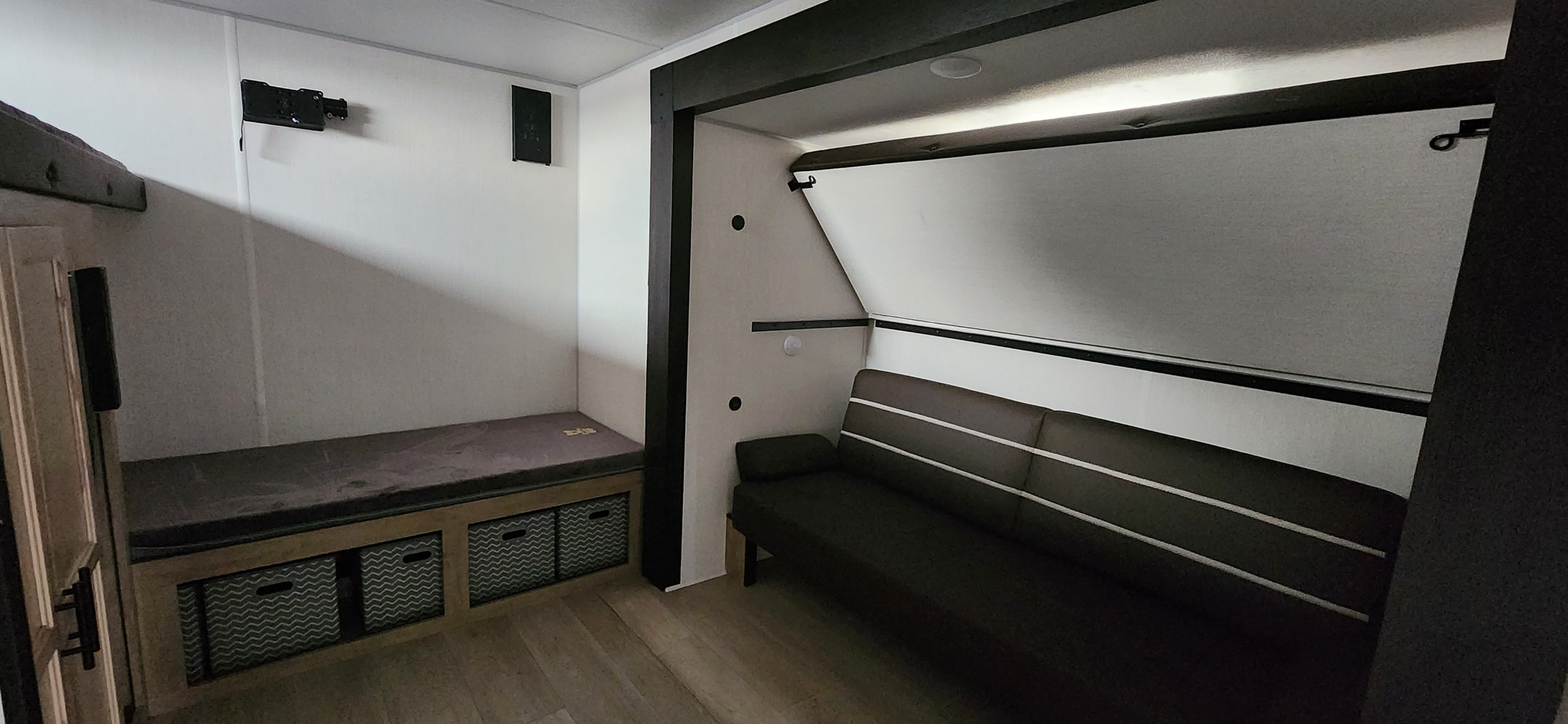 RV rental interior features a cozy bunk area with storage, and a sofa opposite a wall-mounted fold-up bed.. Forest River Cherokee 2026