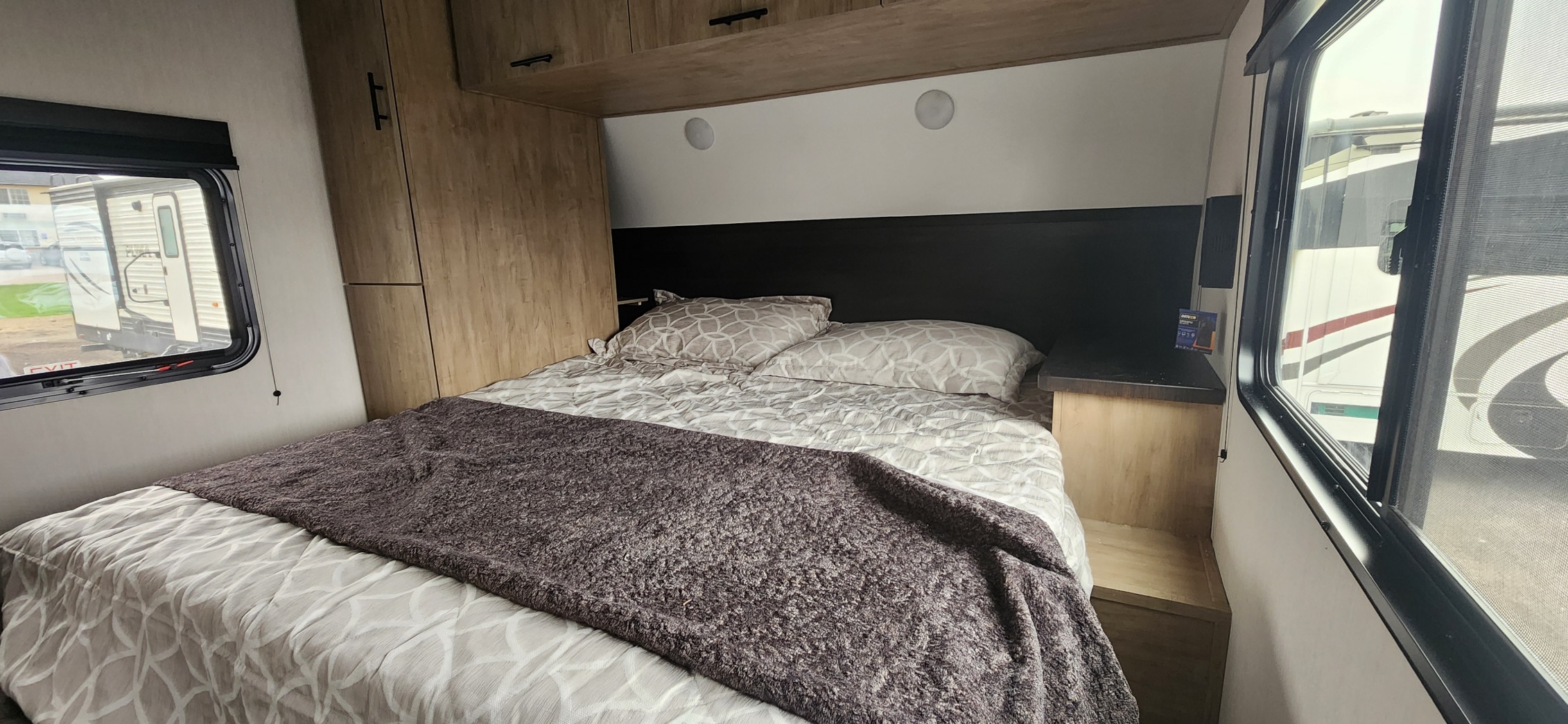 Cozy RV rental bedroom with patterned bedding, built-in storage, and windows showing outdoor scenery.. Forest River Cherokee 2026