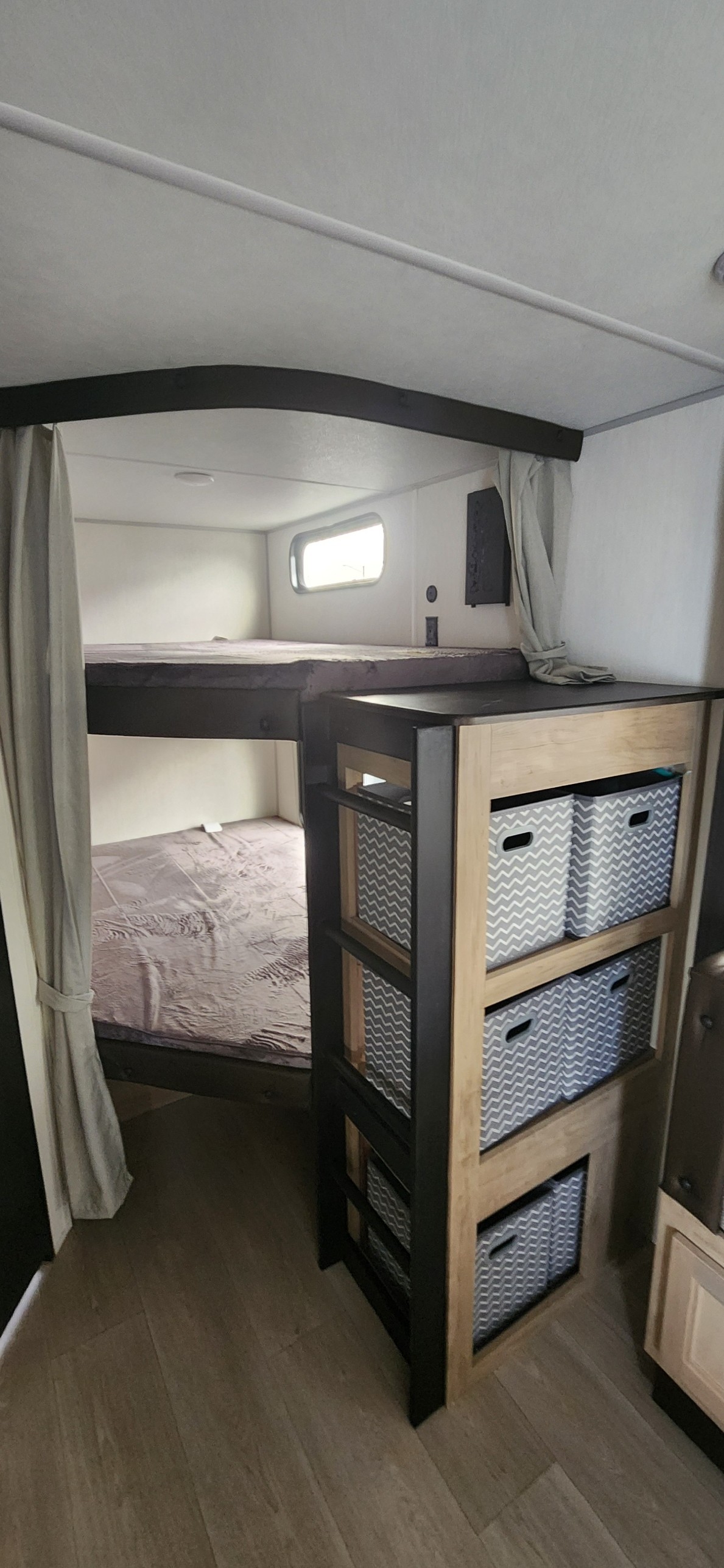 RV rental interior with bunk beds, privacy curtains, and a practical storage unit with patterned bins.. Forest River Cherokee Grey Wolf 2026