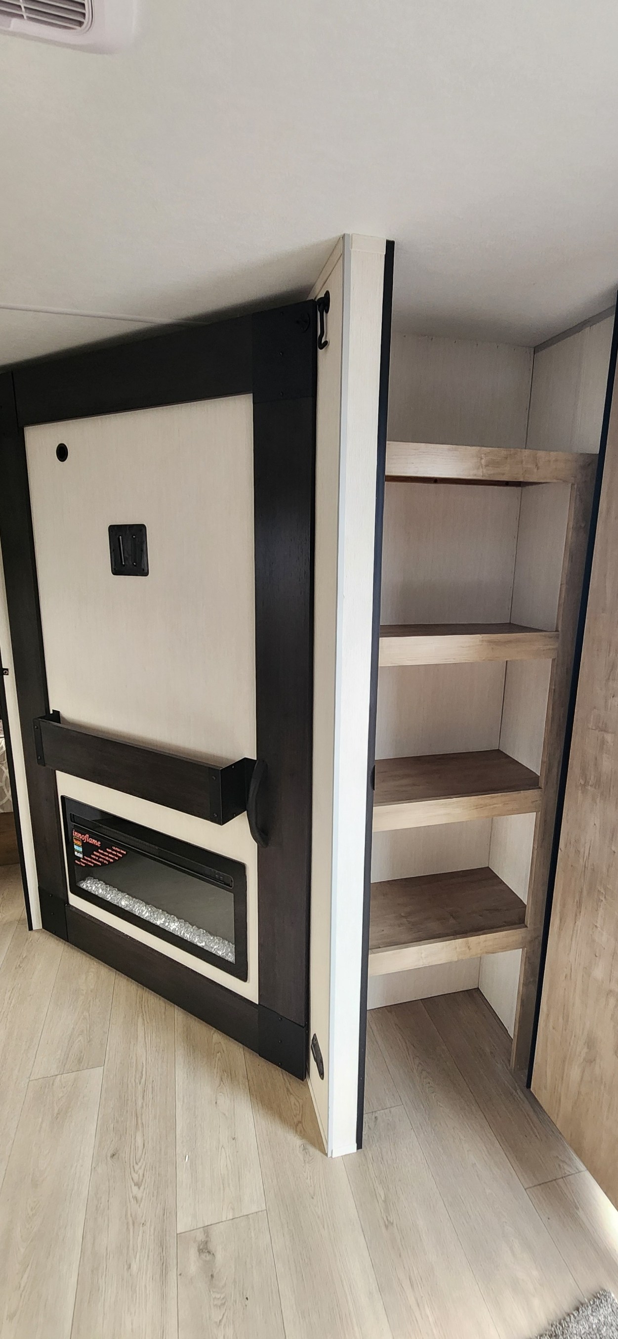 Modern RV rental interior with an electric fireplace, TV mount, and built-in shelving for compact living.. Forest River Cherokee Grey Wolf 2026